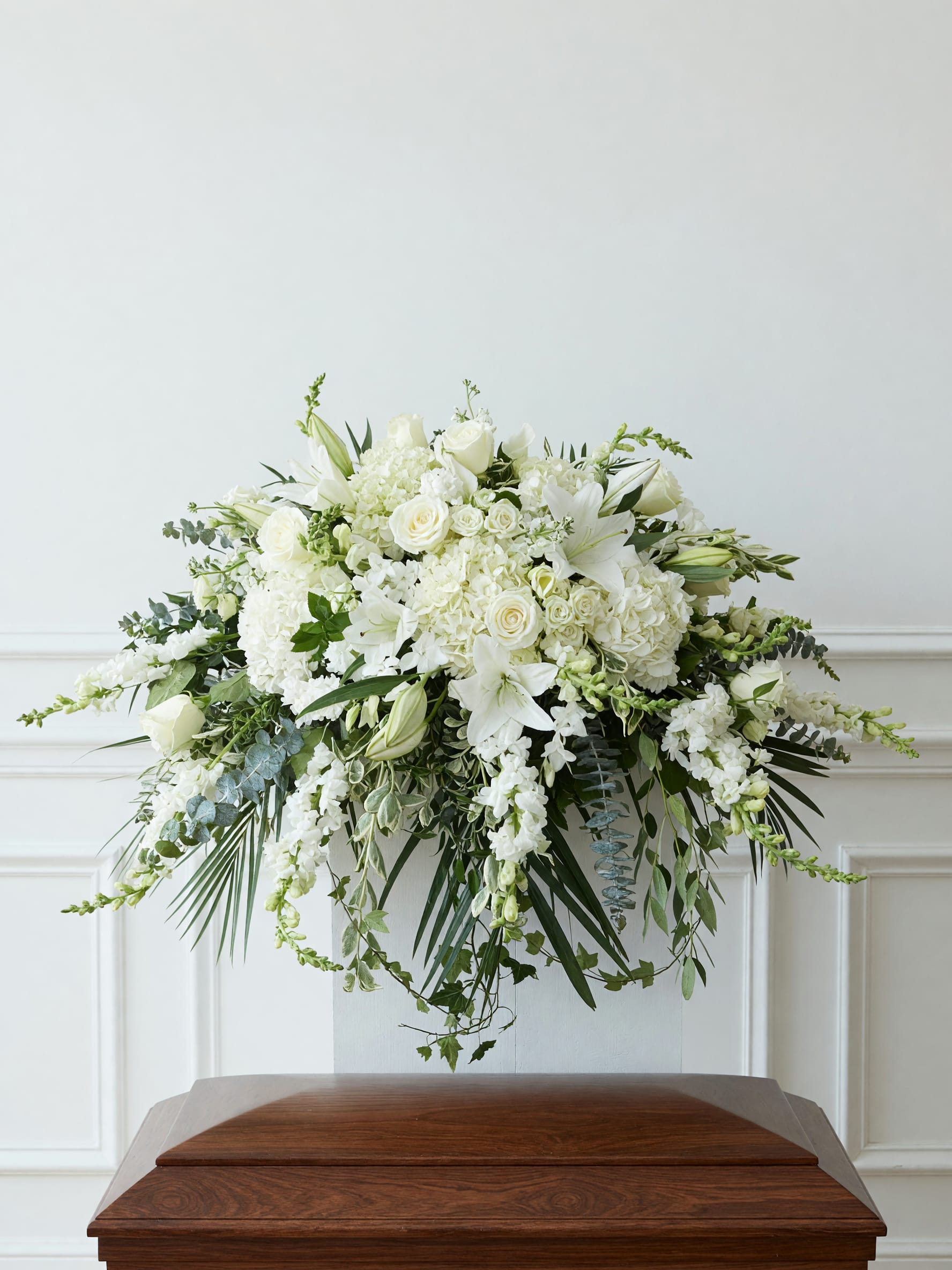 Crystal Casket Cover - The Crystal Casket Cover showcases a sweeping cascade of white hydrangeas, lilies, roses and snapdragons creates a serene casket cover that reads as a quiet, graceful embrace - perfect for sympathy and funeral services