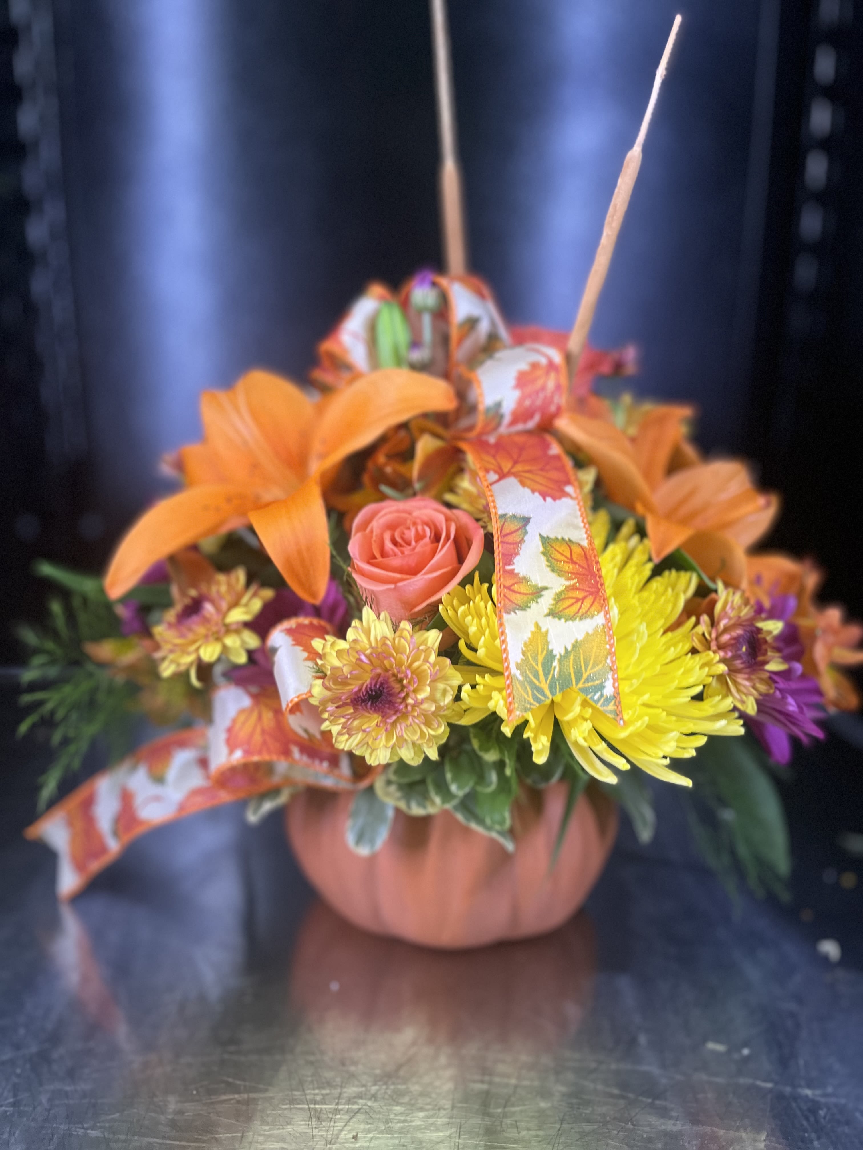 Orange and yellow floral basket with ribbon and a pink rose