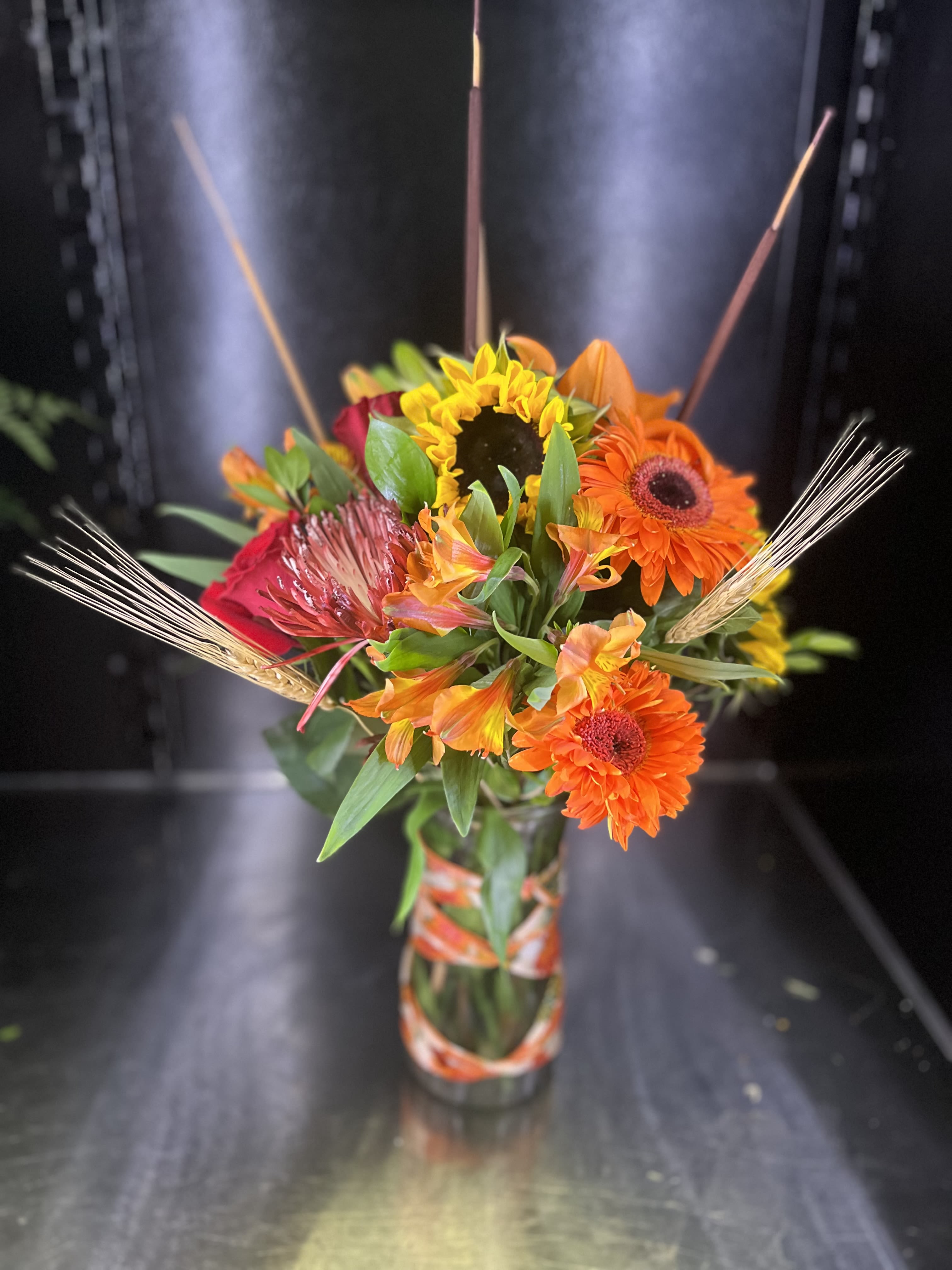 Bright mixed bouquet in a glass vase with orange and yellow blooms