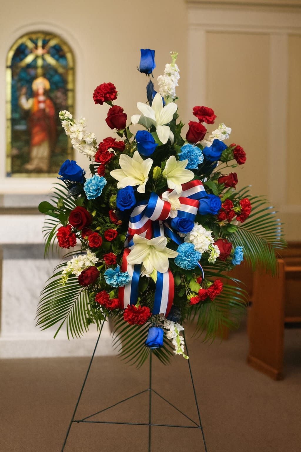 Standing floral spray with red, white, and blue flowers on an easel