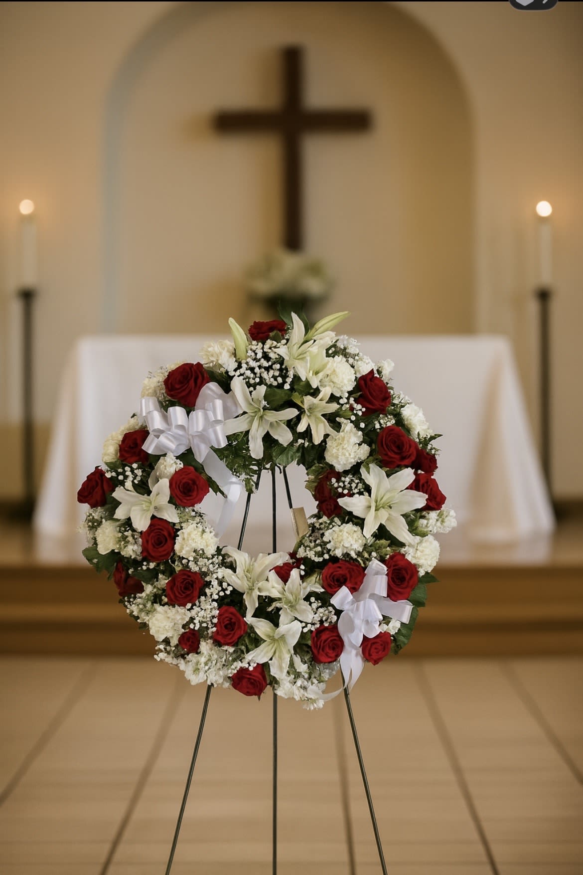 Red and white floral funeral wreath on a stand in a church
