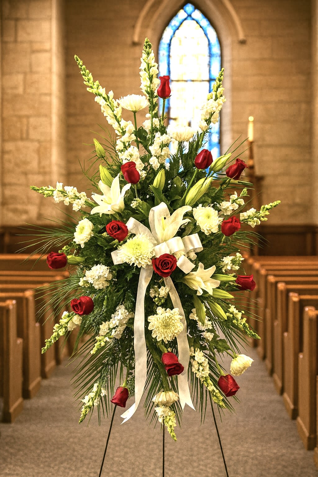 Standing funeral spray with red roses and white lilies on an easel