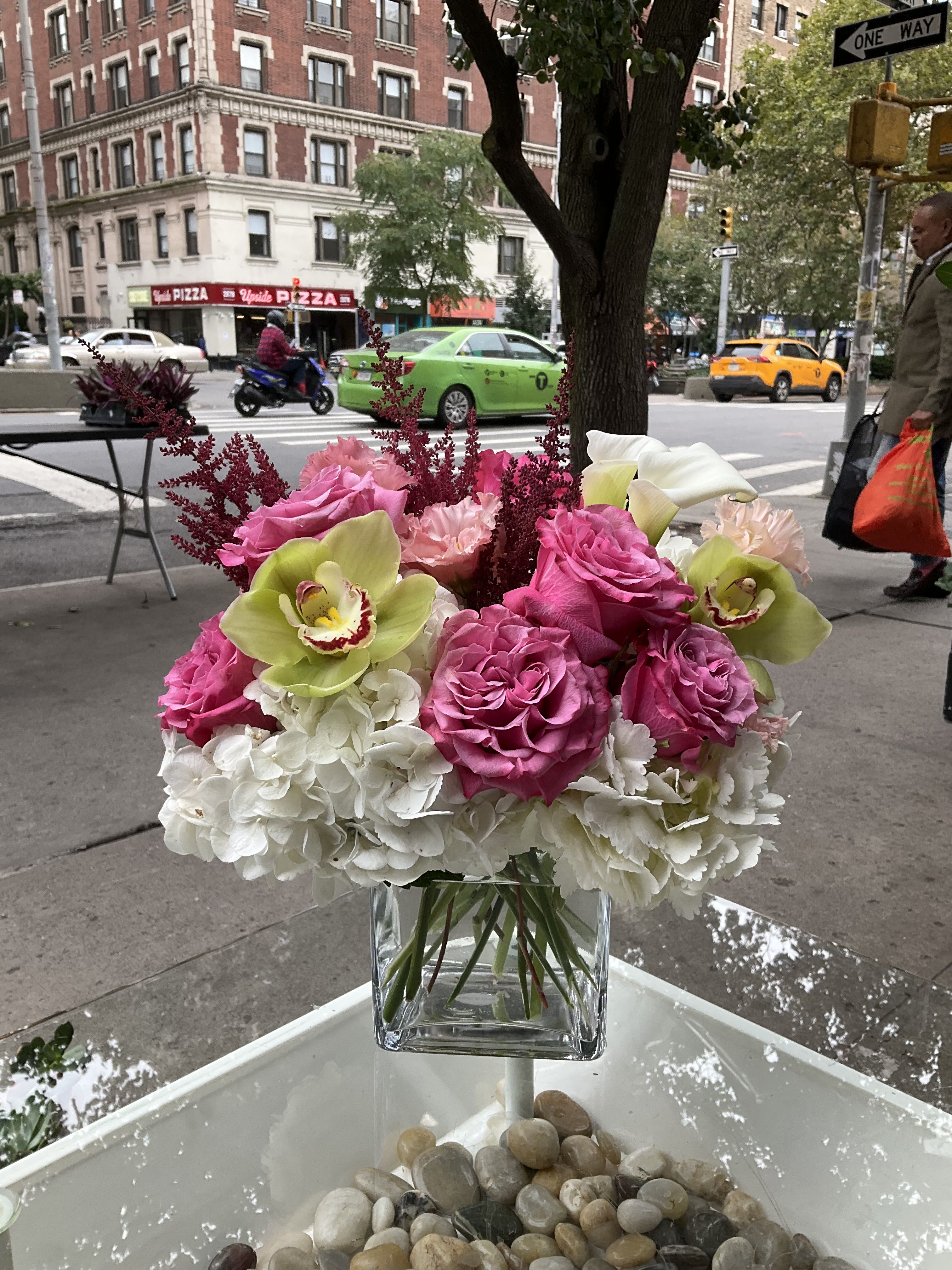 Midnight Velvet Garden - A bold and beautifully designed arrangement featuring vibrant purple blooms, fresh green orchids, and soft white hydrangeas, accented with deep velvet-toned flowers for a rich, elegant finish. This piece is designed to stand out with its striking color contrast and lush, layered texture, making it perfect for any special moment that calls for something truly beautiful.  Please note that flowers and specific varieties may vary based on daily availability. Our inventory changes quickly, but we always do our best to maintain the same overall look, color palette, and style using the freshest flowers available.