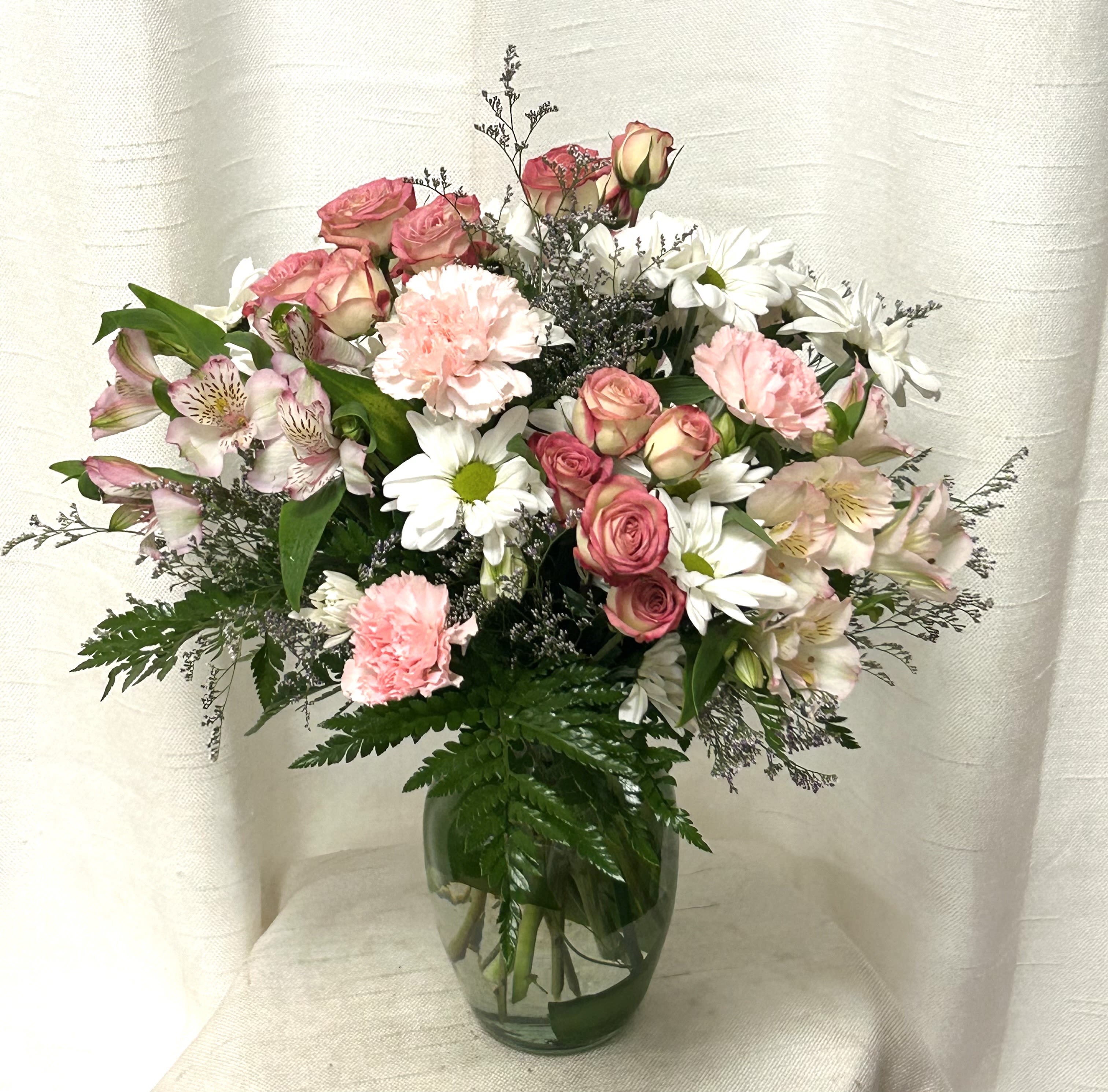 Pink roses, carnations, and white daisies in a glass vase