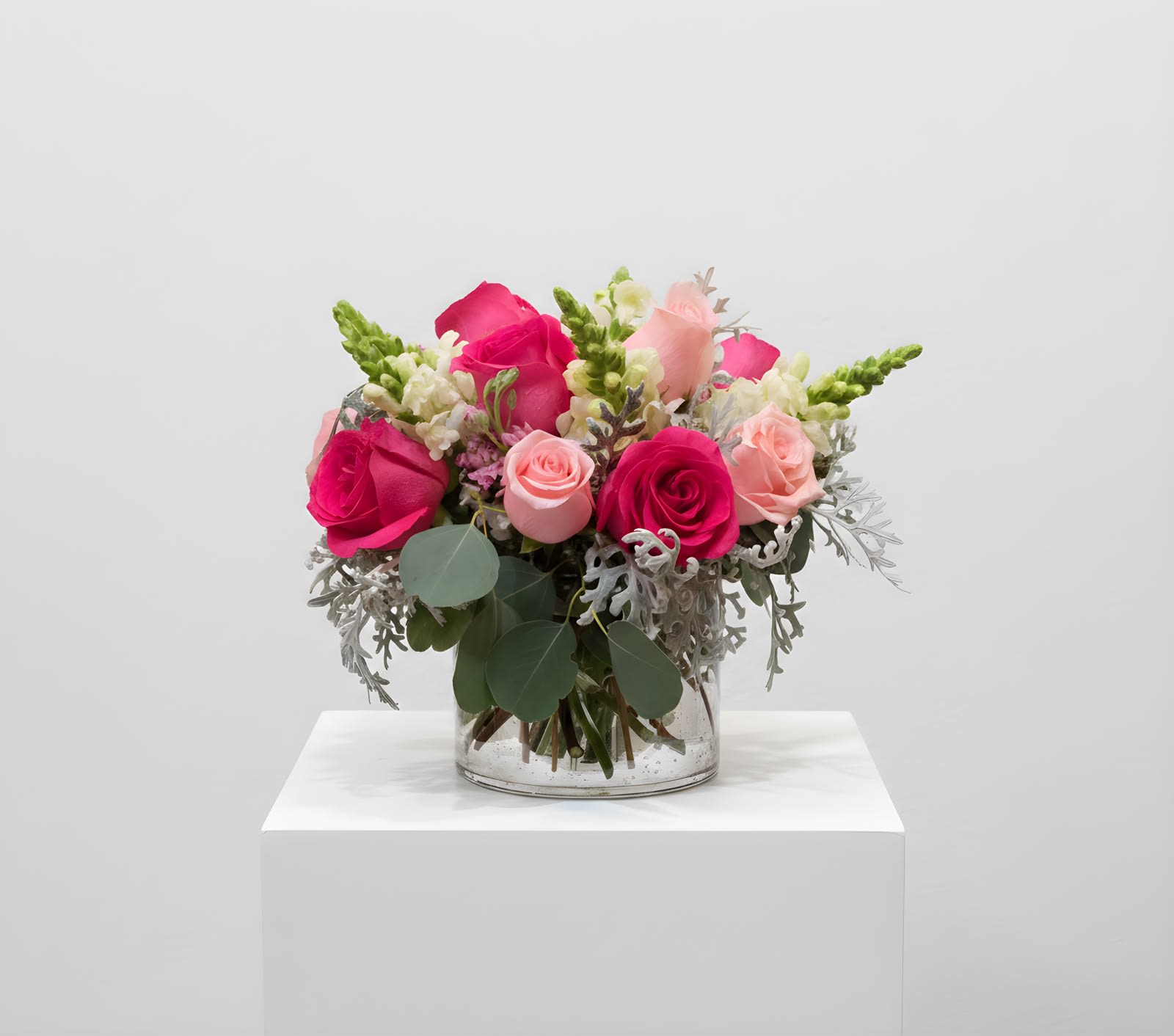 Let's Dance - Put on your red shoes and dance, because this arrangement is a stunner! Sprigs of snapdragons add energy to roses, dusty miller, and hints of eucalyptus. This arrangement is round and comes in a glass vase. 