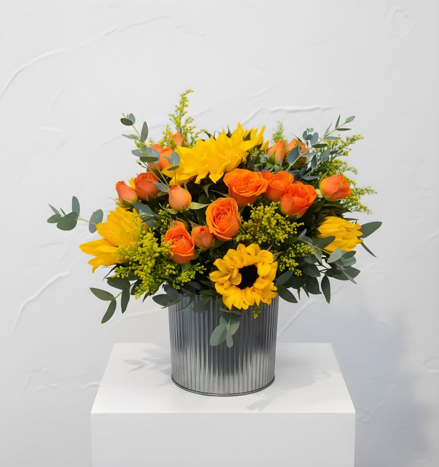 Citrus Glow - Bright yellow sunflowers and clustered orange roses create an exuberant birthday bouquet that instantly brightens a room - the kind of arrangement that makes the person you're thinking of feel seen and celebrated. Designed for everyday celebrations and uplifted moments, this cheerful mix pairs bold blooms with soft, airy greenery to balance warmth and visual energy.