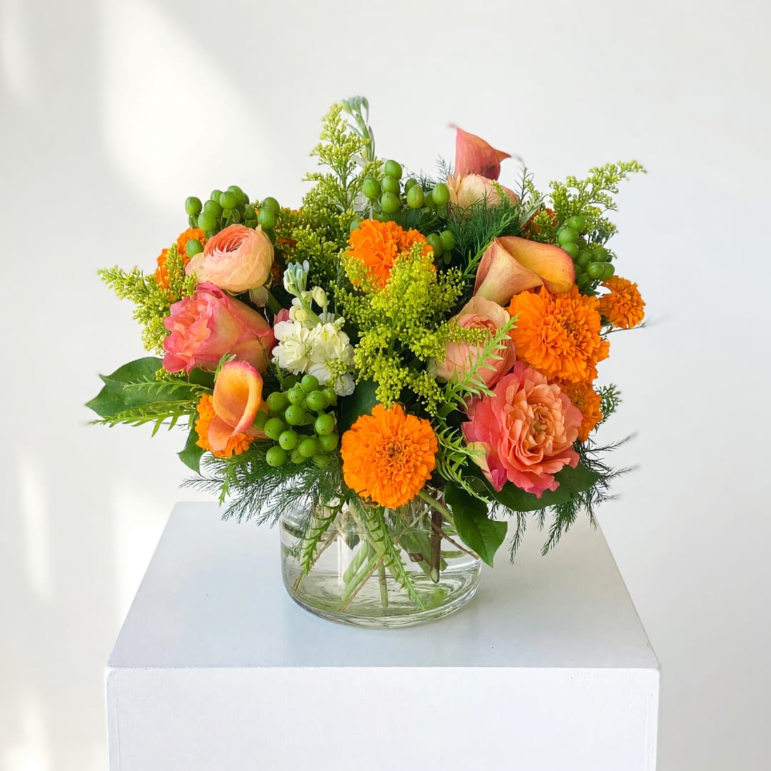 Colorful bouquet in a clear glass vase with orange, pink, and white blooms