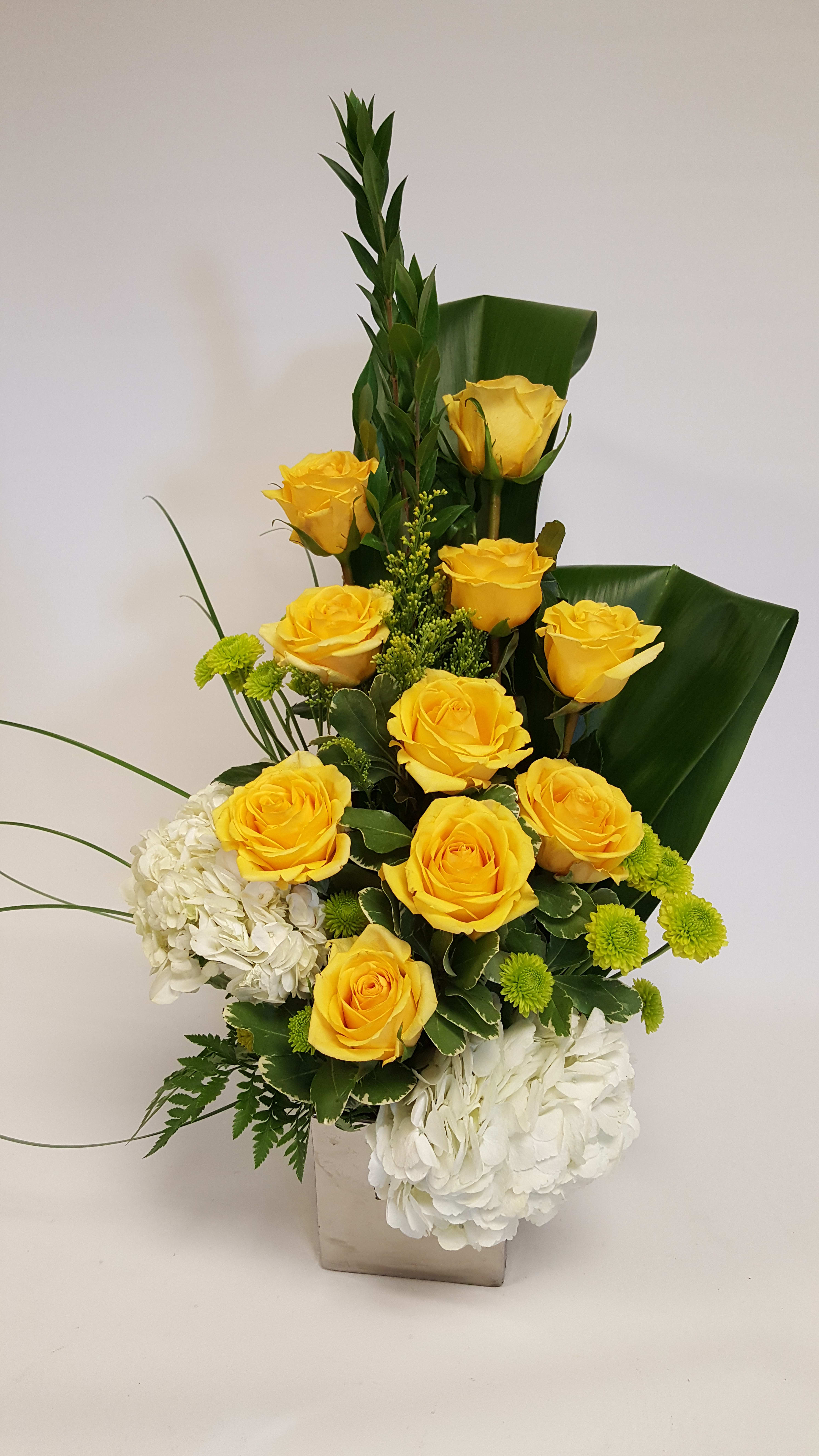 Yellow roses and white hydrangeas in a square vase