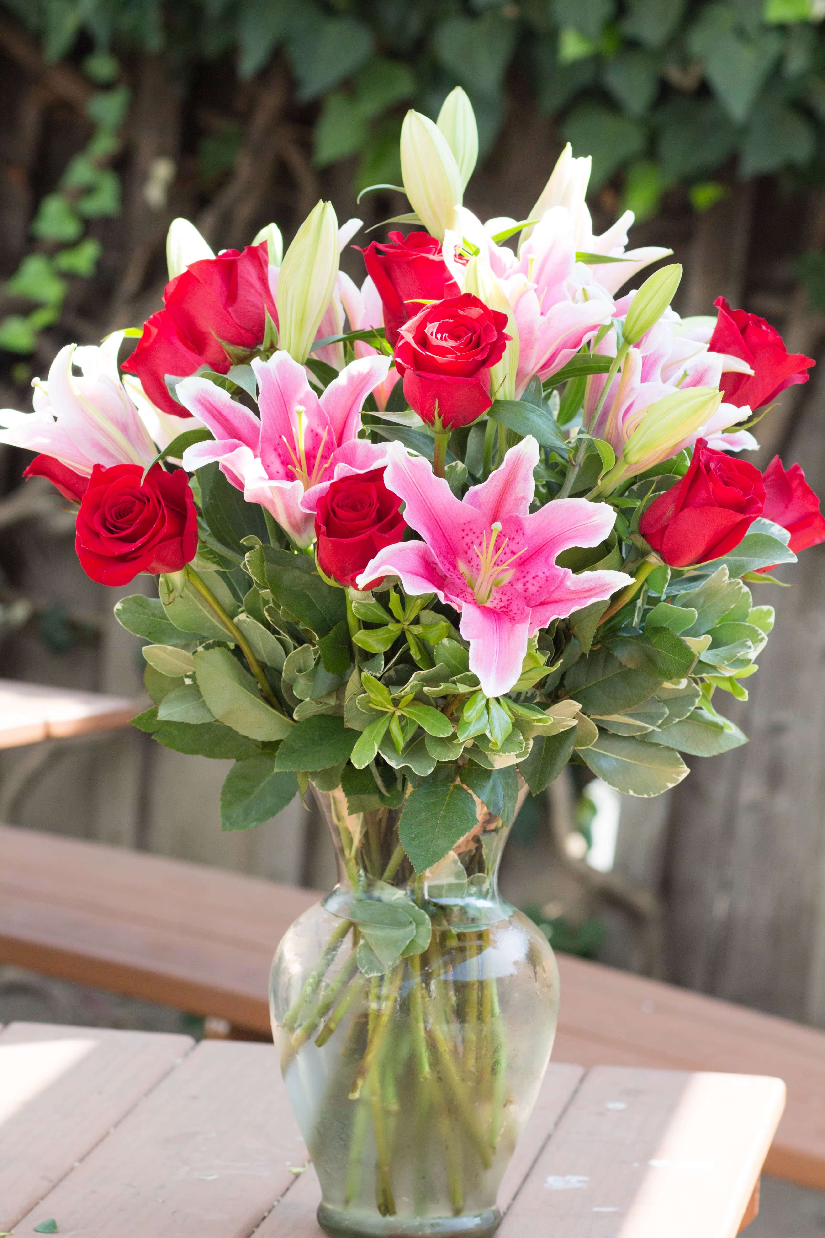 Bouquet of red roses and pink lilies in a glass vase