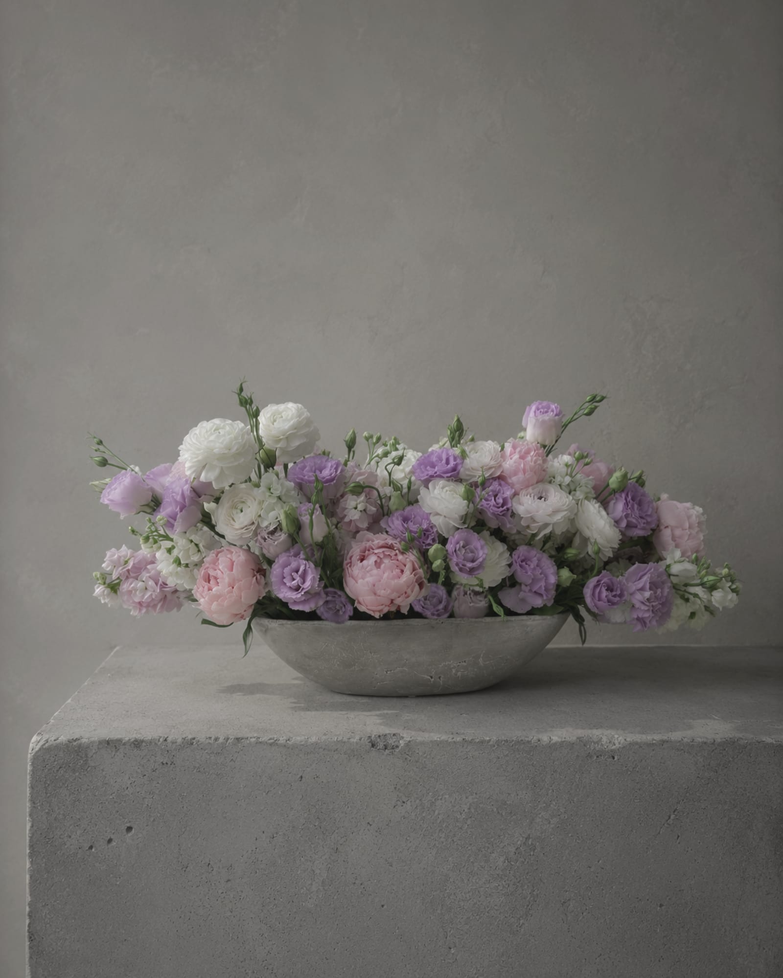 Low pastel flower arrangement in a shallow gray bowl