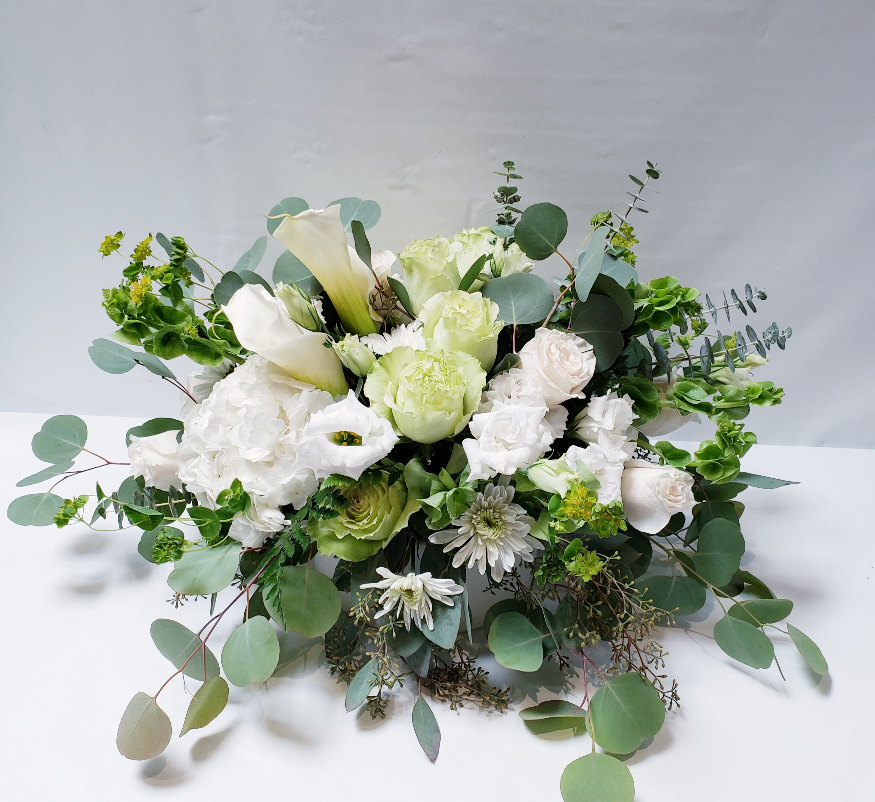 White and pale green floral arrangement with calla lilies and roses