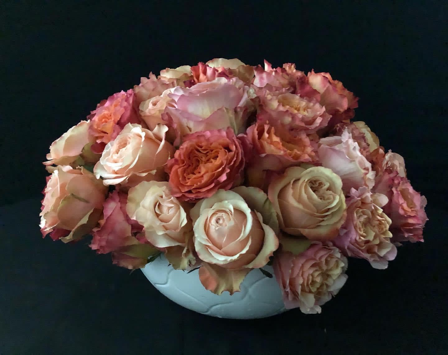 Pink and peach roses arranged in a white vase
