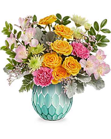 Mixed bouquet of yellow roses, pink carnations, and pale flowers in a turquoise vase