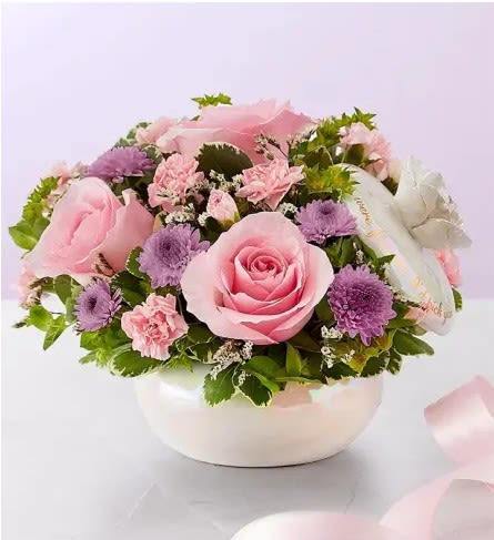 If Mothers were Flowers - All-around arrangement with light pink roses and mini carnations, pink Limonium and lavender button poms; accented with assorted greenery Artistically designed in our exclusive container, designed in an iridescent finish on a ceramic base, embellished with a budding rose and finished with a gold foil sentiment, “If mothers were flowers I’d pick you”. This brilliant pearl colored ceramic Dish has a rose handle top that can be used by Mom as a jewelry box!!  Measures 4.5"H x 5.87"D