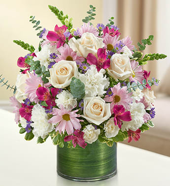 Cherished Memories - Lavender and White - Product ID: 95421   Remember a loved one with elegance and grace by sending our peaceful lavender and white arrangement in a classic cylinder vase. The freshest roses, snapdragons, alstroemeria, carnations and more are gathered by our florists to offer a tribute to a beautiful life. Graceful lavender and white arrangement of roses, snapdragons, alstroemeria, carnations, daisy poms, mini carnations and monte casino, gathered with variegated pittosporum and spiral eucalyptus Hand-designed by our expert florists in a stylish clear glass cylinder vase wrapped with a Ti leaf ribbon; vase measures 6"H Appropriate for the service or the home of friends and family members Large arrangement measures approximately 16"H x 17"L Medium arrangement measures approximately 15"H x 16"L Small arrangement measures approximately 14"H X 15"L Our florists hand-design each arrangement, so colors, varieties, and vase may vary due to local availability