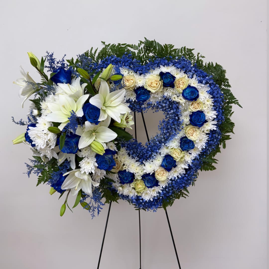 Heart-shaped floral wreath with blue and white flowers on a stand