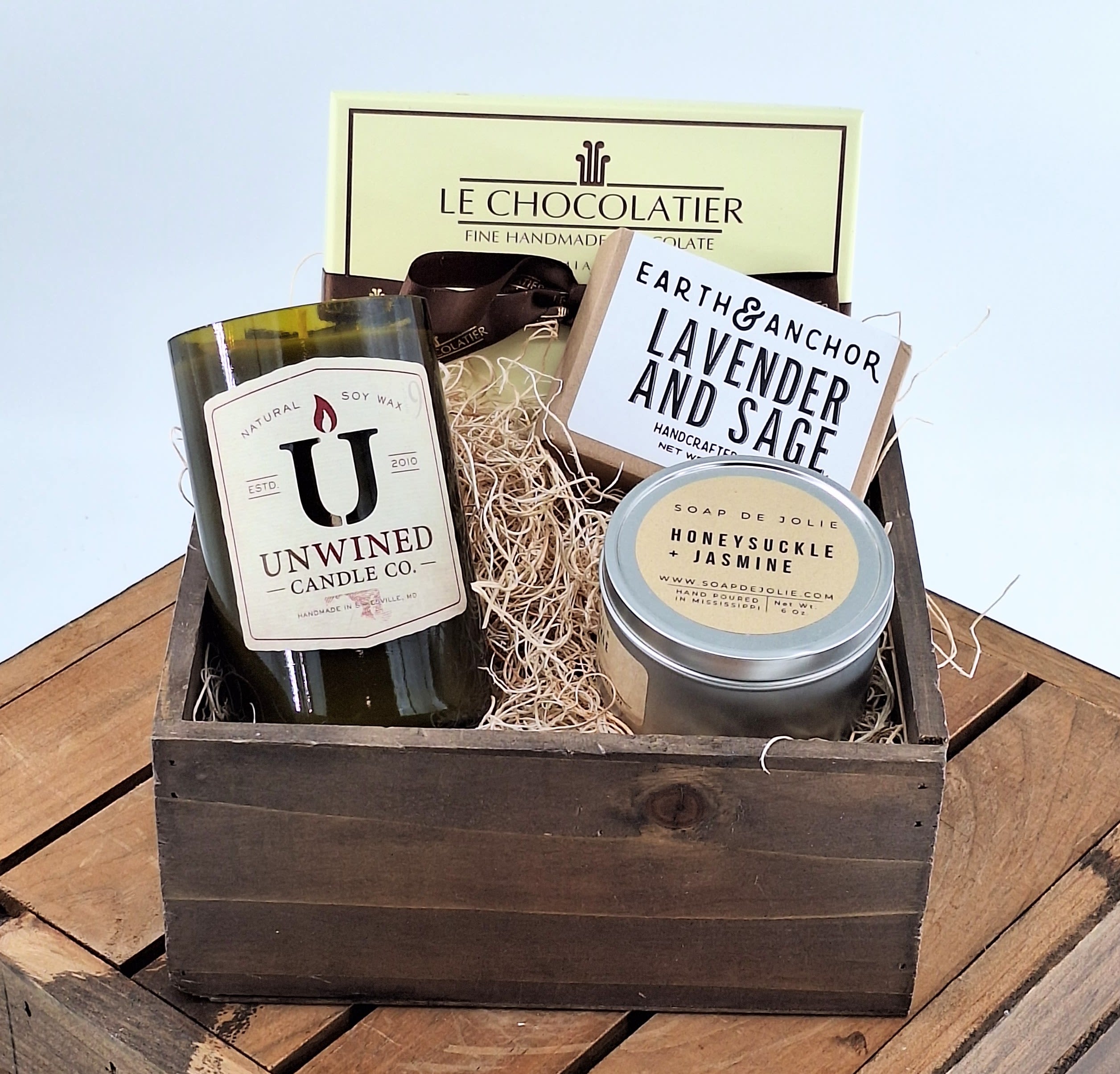 Gift basket with chocolates, candles, and soap in a wooden crate