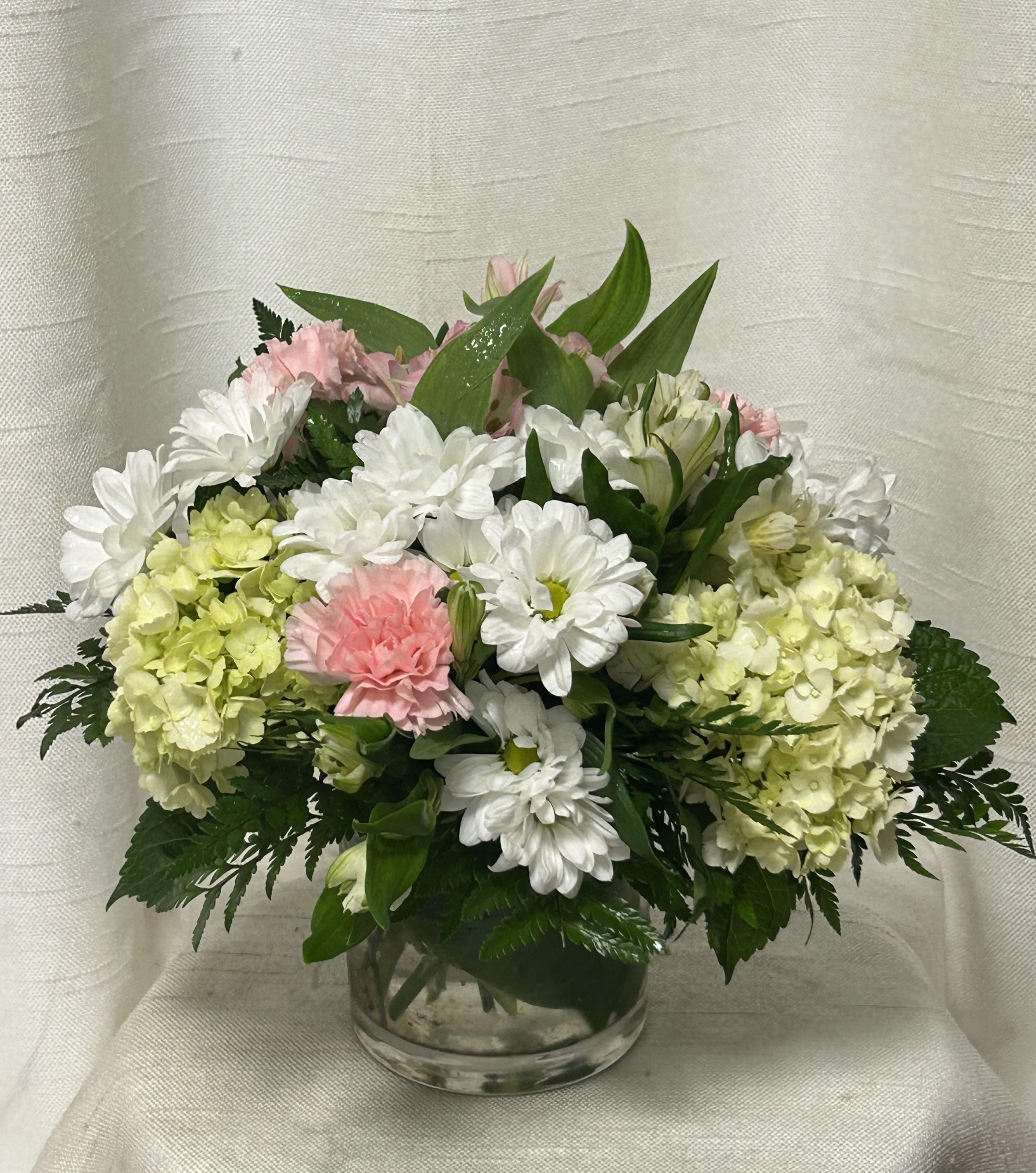 Pink and white flowers arranged in a clear glass vase