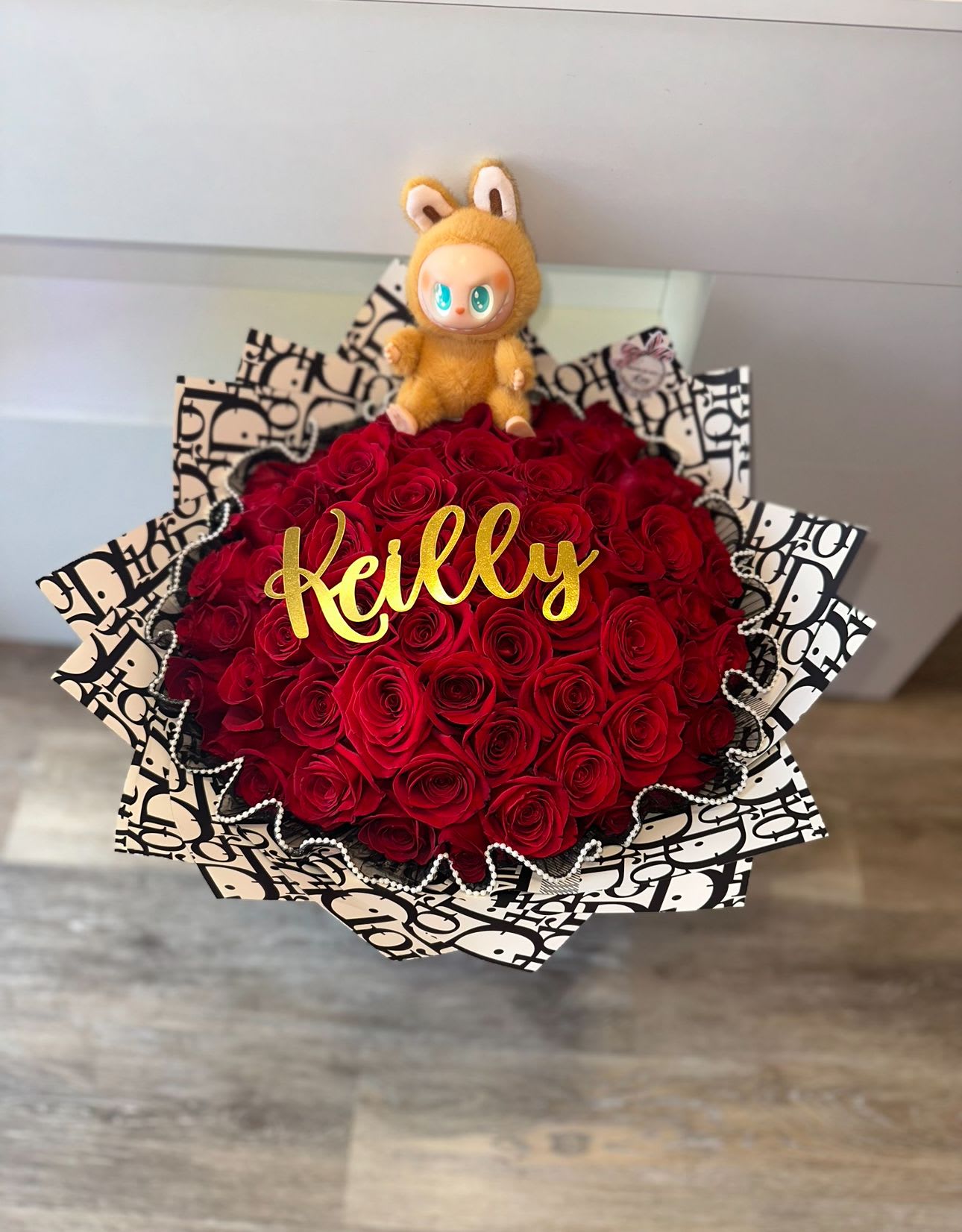 Red rose bouquet with a small plush toy and gold name topper