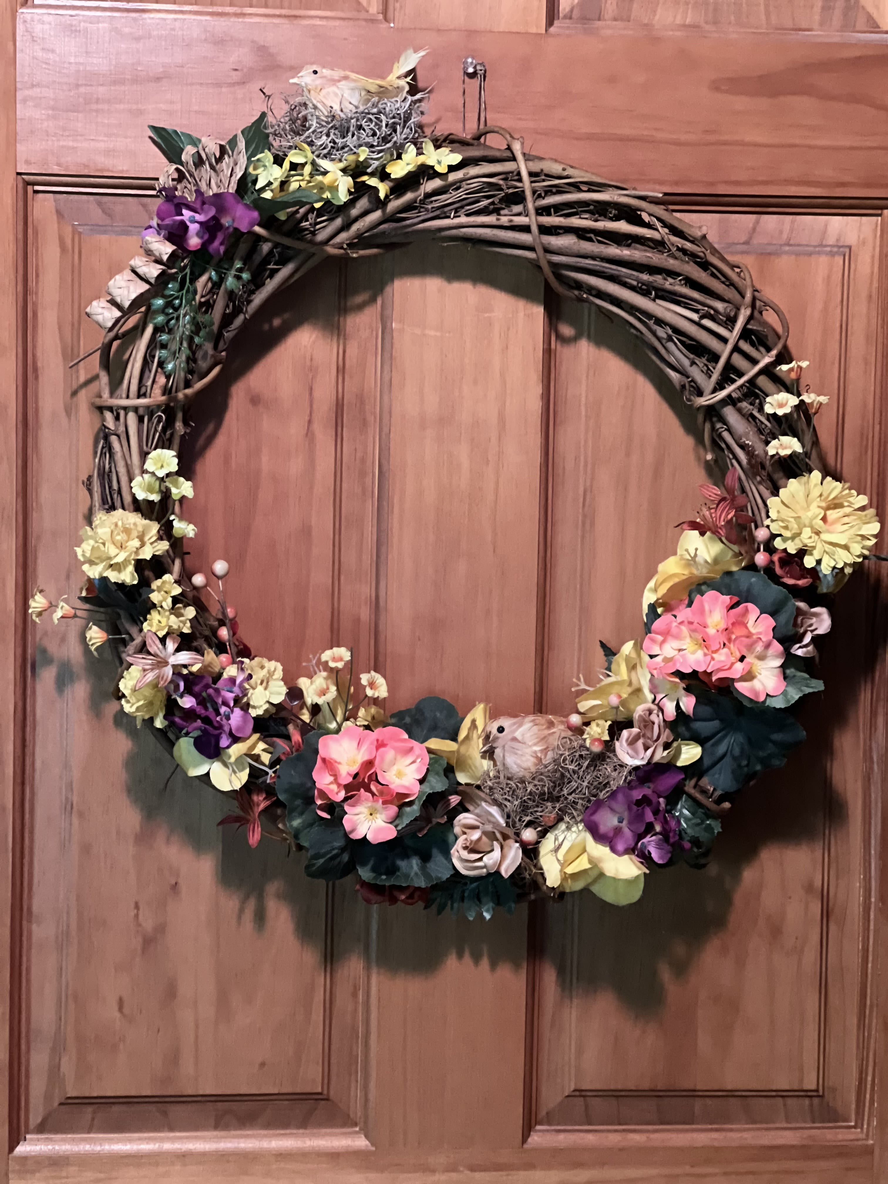 Floral wreath with pink, yellow, and purple flowers on a twig frame