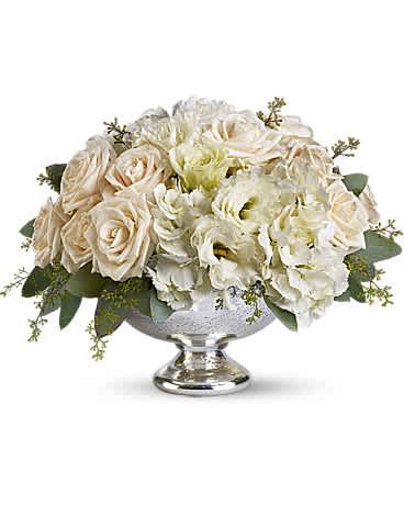Low centerpiece of cream roses and white hydrangeas in a silver pedestal bowl