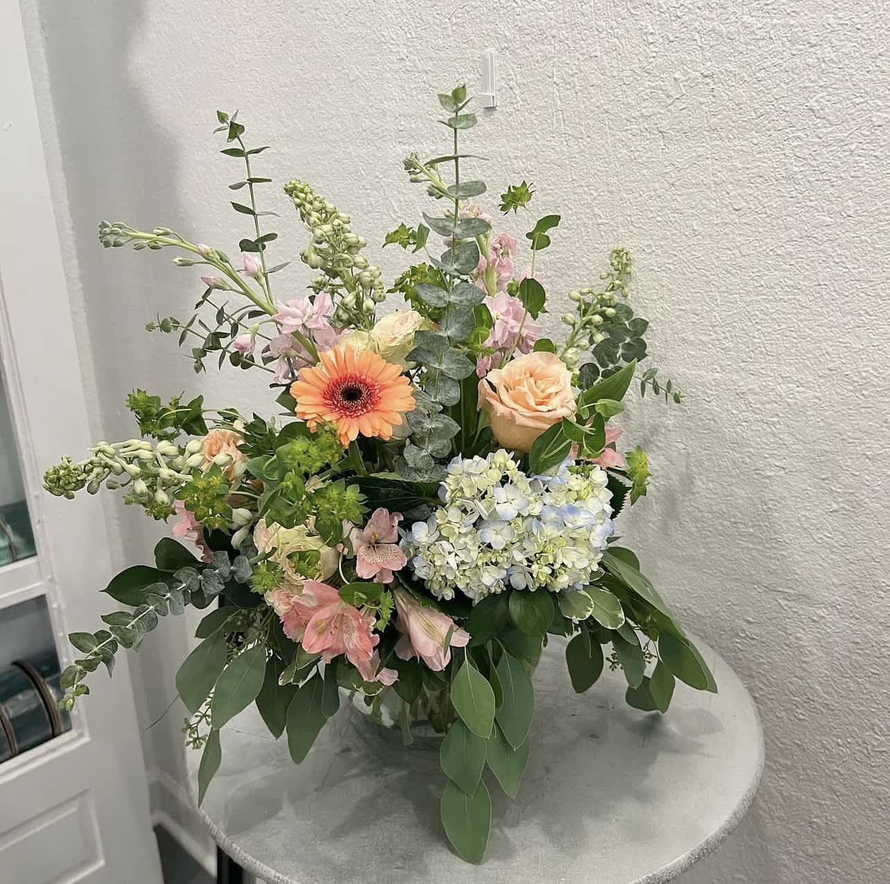 Mixed floral arrangement with peach roses, gerbera daisy, and hydrangea in a vase