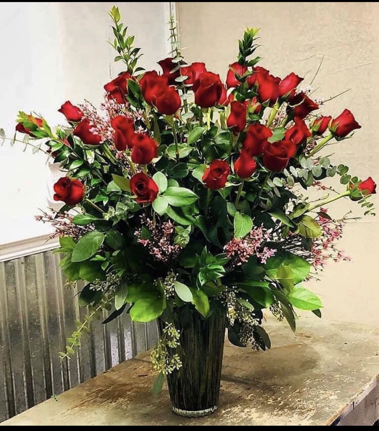 Tall bouquet of red roses in a clear glass vase