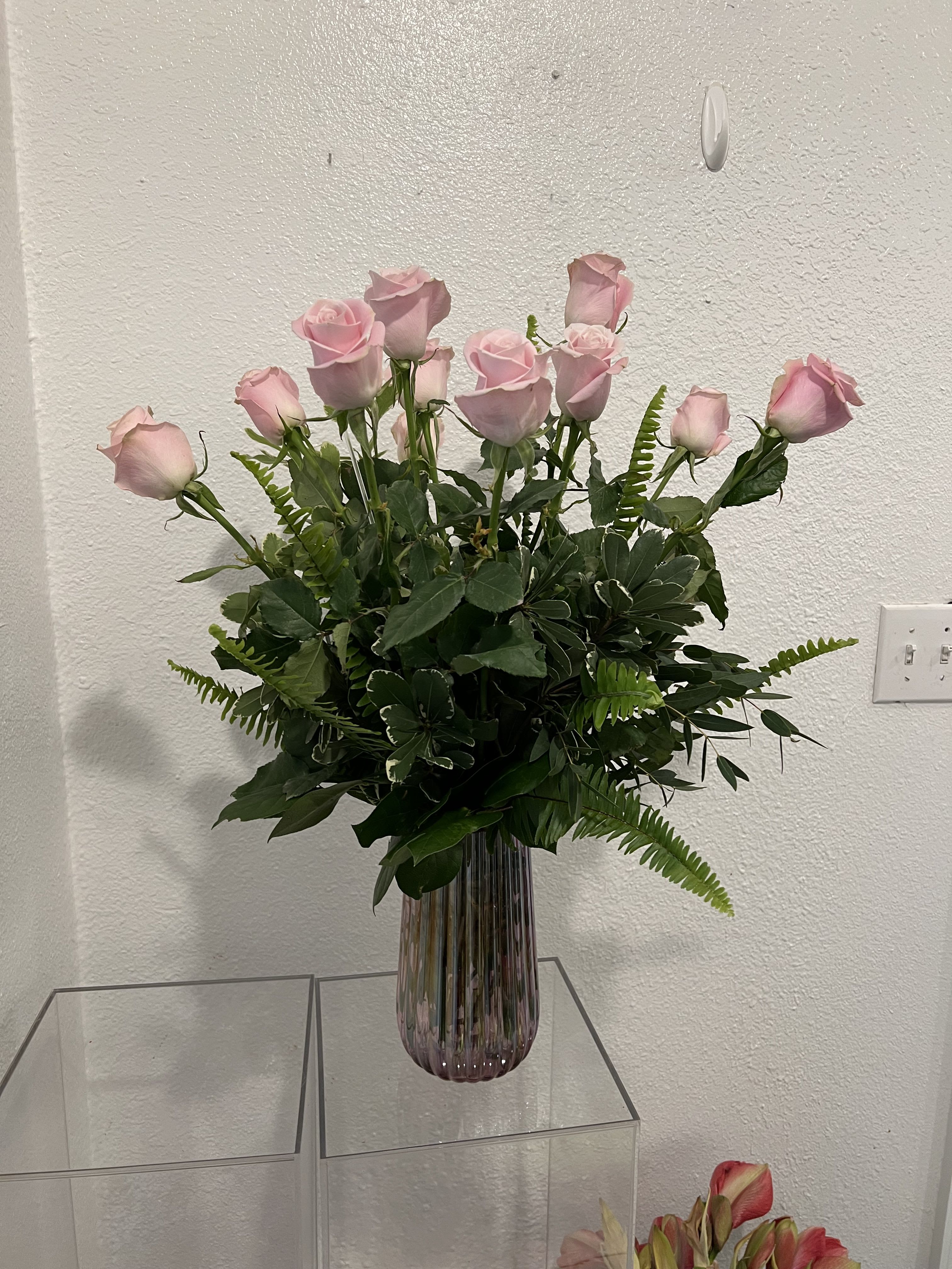 Pink roses arranged in a tall ribbed glass vase