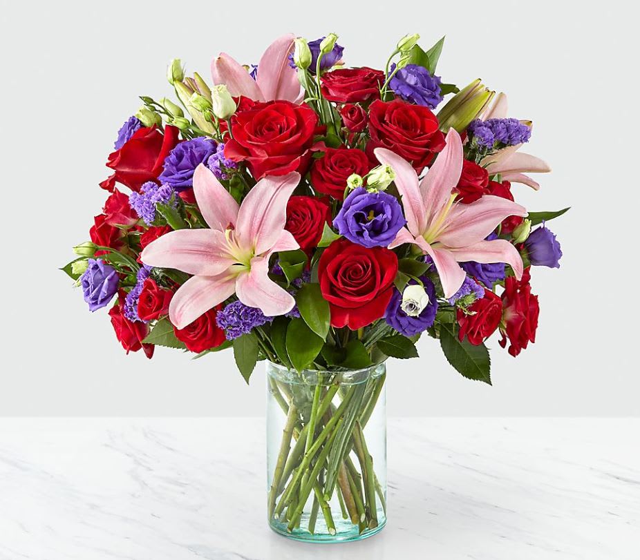 The Truly Stunning Bouquet - Share a smile with your loved ones through a bouquet filled with stunning beauty and heartfelt joy. Comprised of vivid red roses, purple double lisianthus, pink lilies and red spray roses within a clear glass vase, vibrant color bursts from every bloom. Make their day brighter with a gift that is Truly Stunning™!  