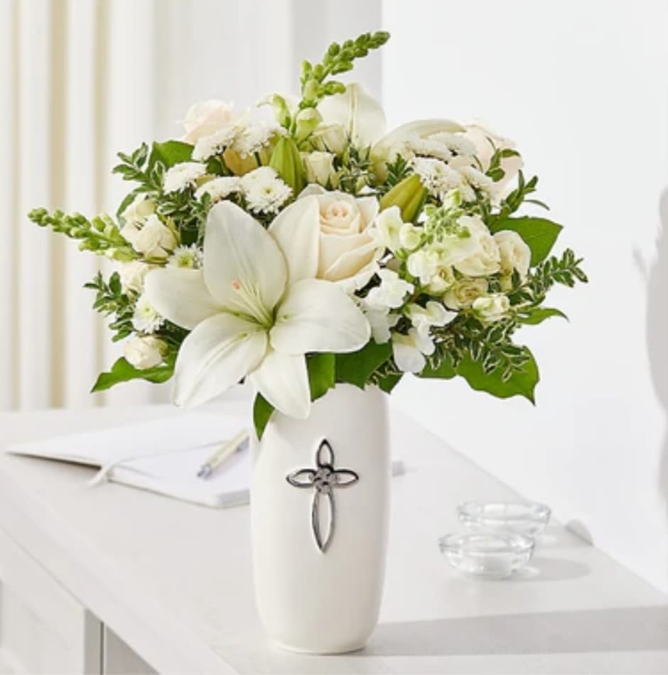 White floral arrangement in a tall vase with a cross emblem