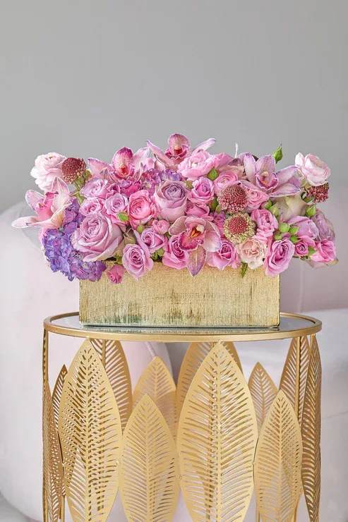 Pink and lavender floral arrangement in a gold rectangular box