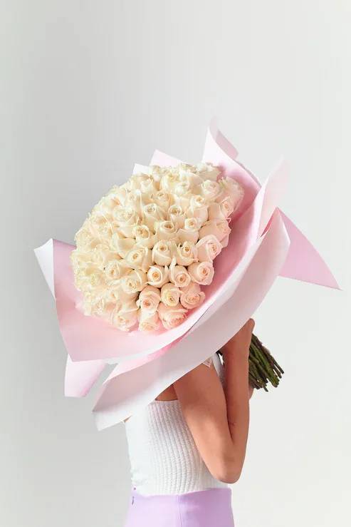 Large bouquet of pale cream roses wrapped in pink paper
