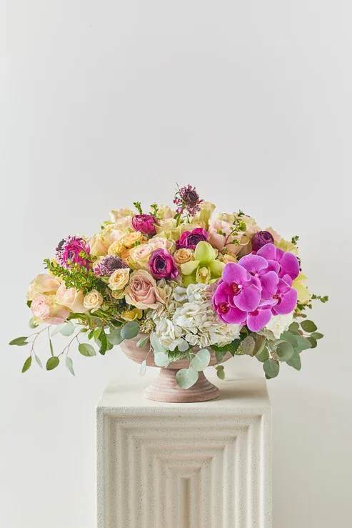Mixed pink and cream floral arrangement in a pedestal bowl