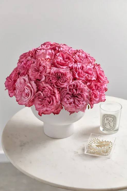 Pink rose bouquet in a white vase on a round table