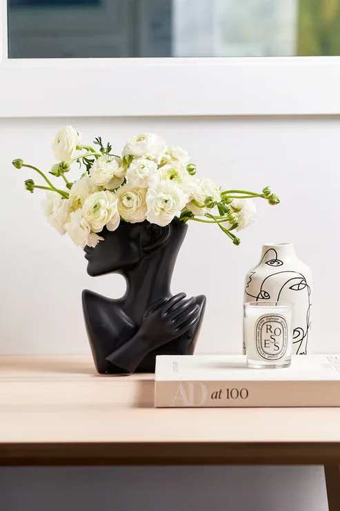 White ranunculus arrangement in a black sculptural vase