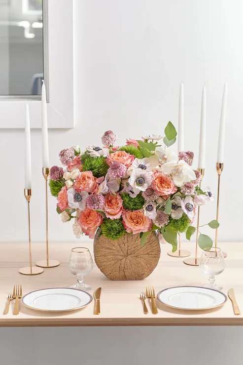 Pink and white floral centerpiece in a round woven vase on a table