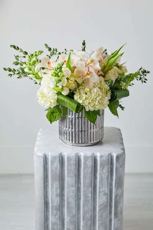 White and pale peach floral arrangement in a silver vase