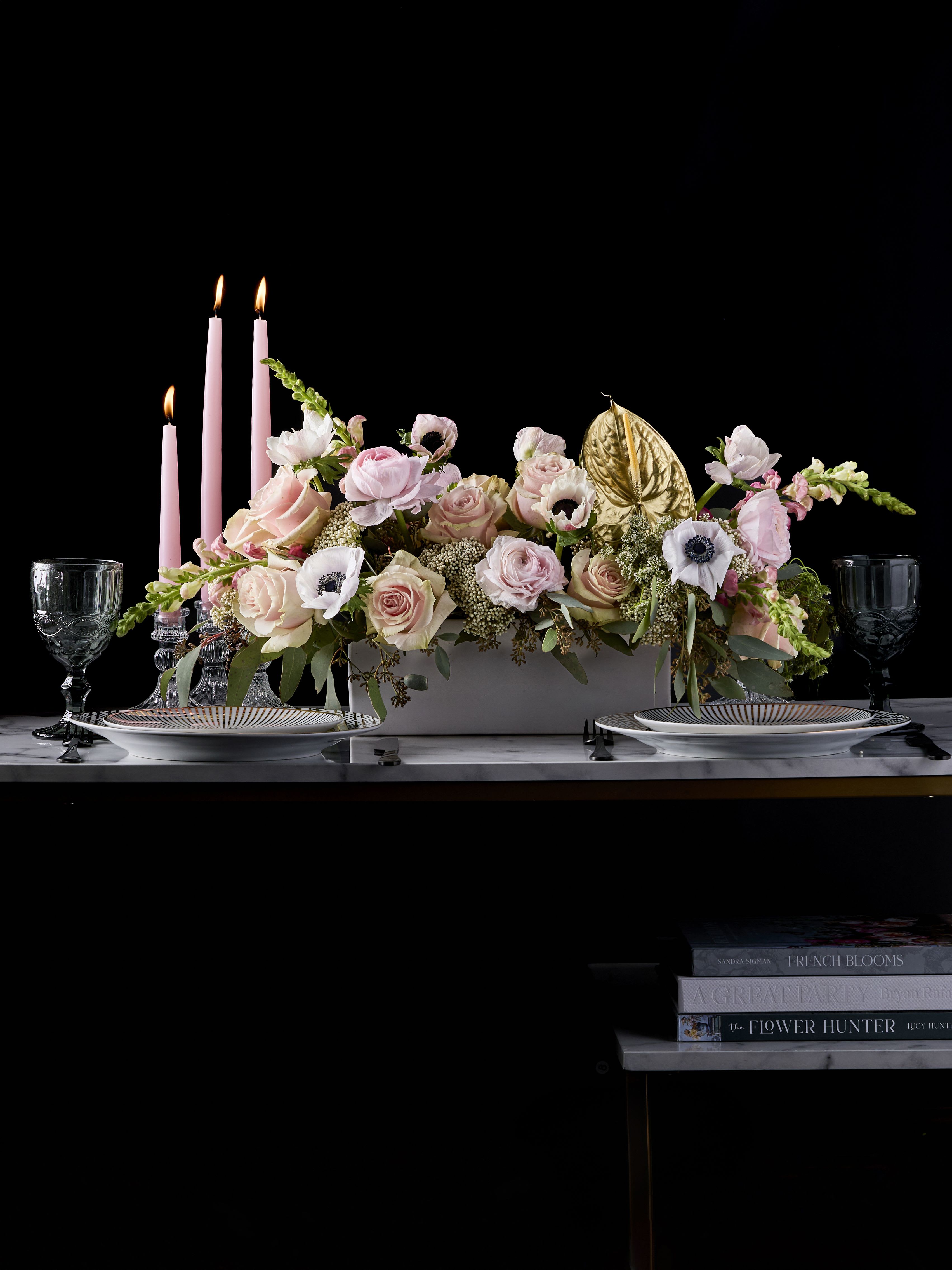 Pink floral centerpiece with candles and gold accent on a table
