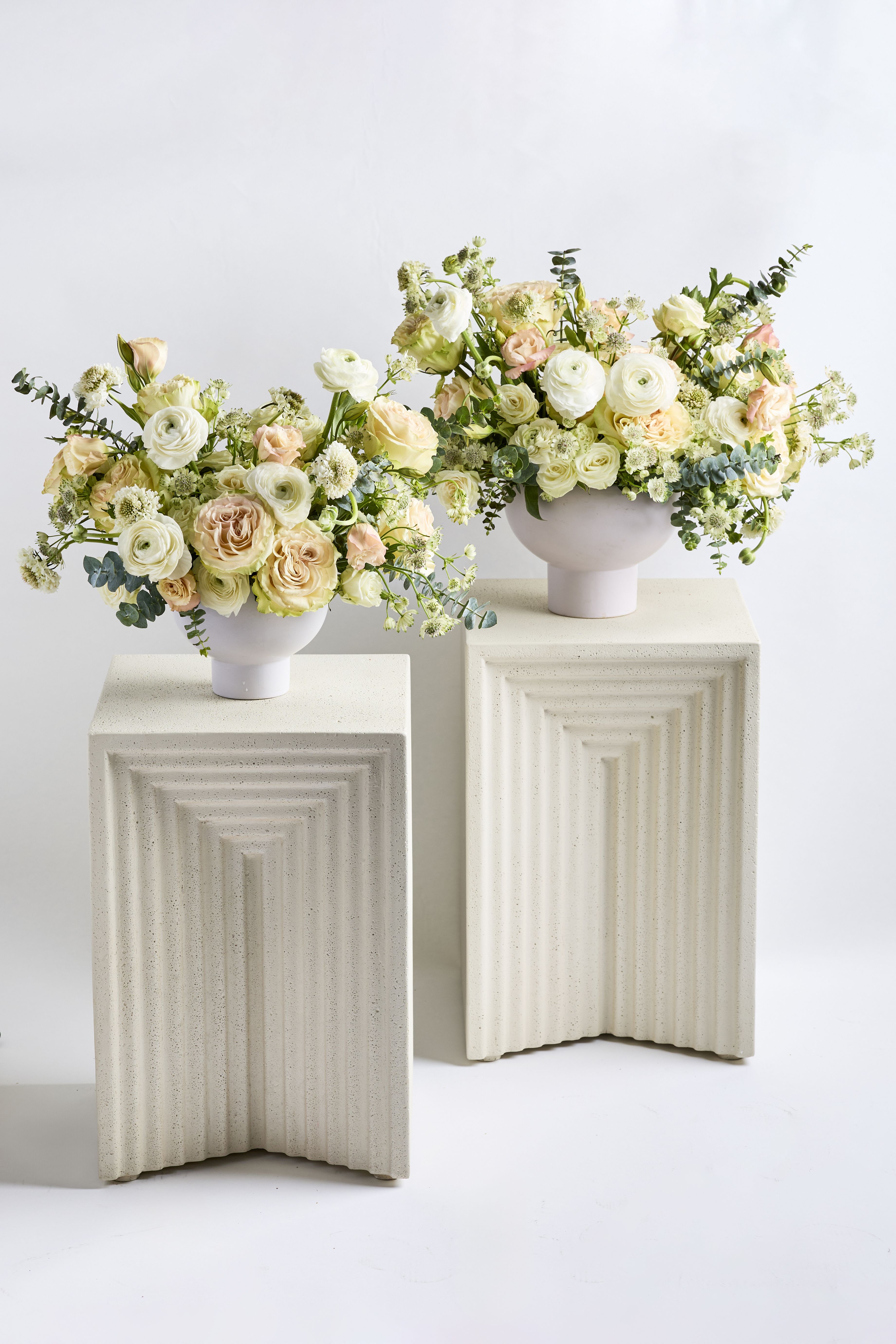 Two pastel floral arrangements in white pedestal vases