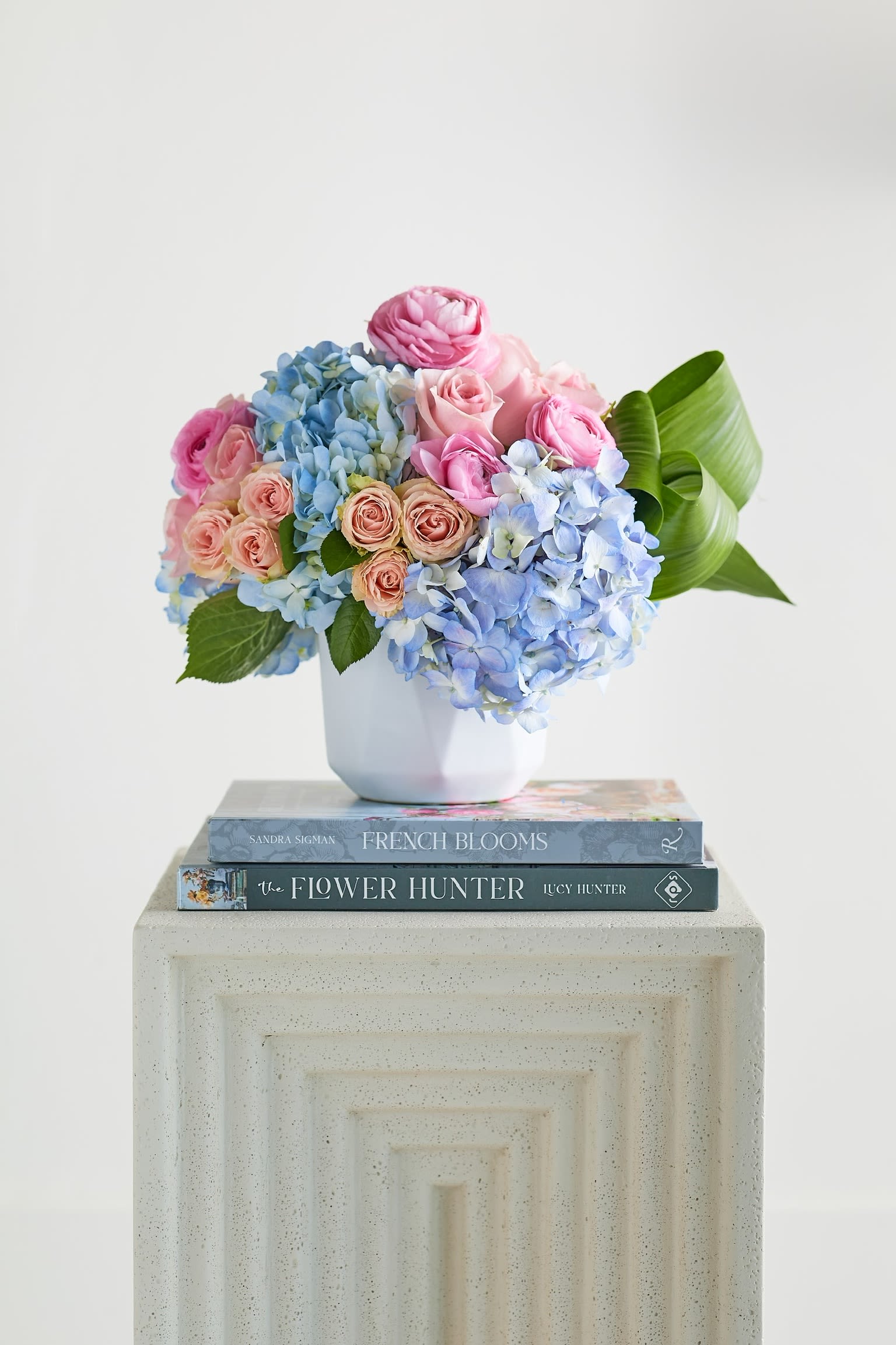 Pink roses and blue hydrangeas in a white vase