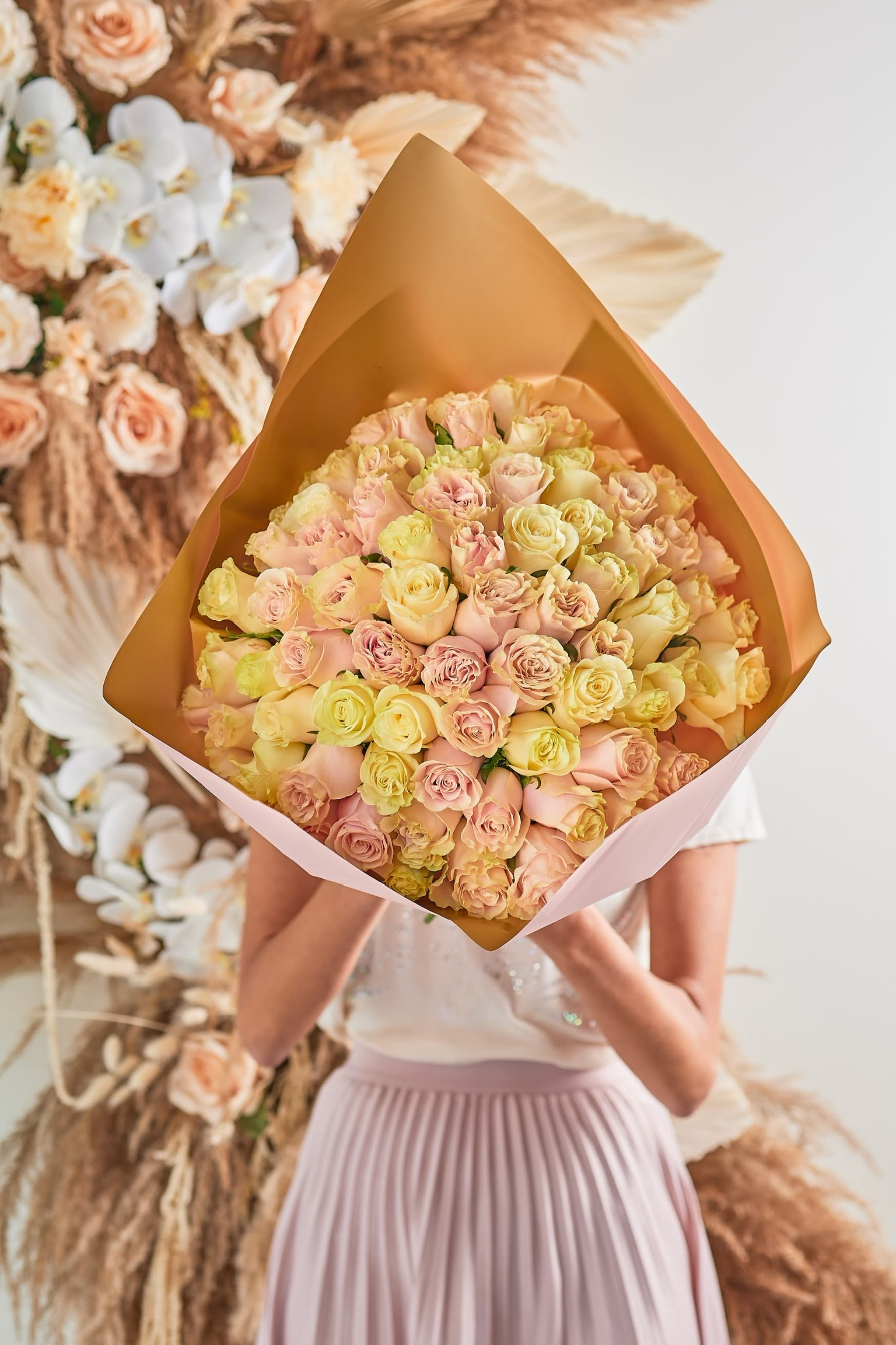 Large bouquet of pale pink and cream roses wrapped in tan paper