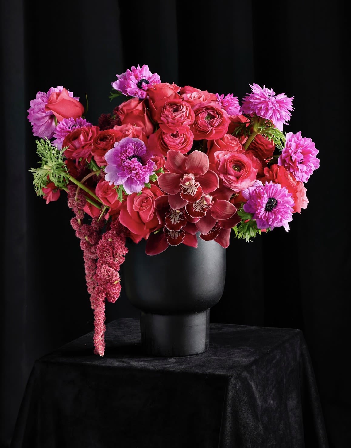 Pink and red floral arrangement in a black vase
