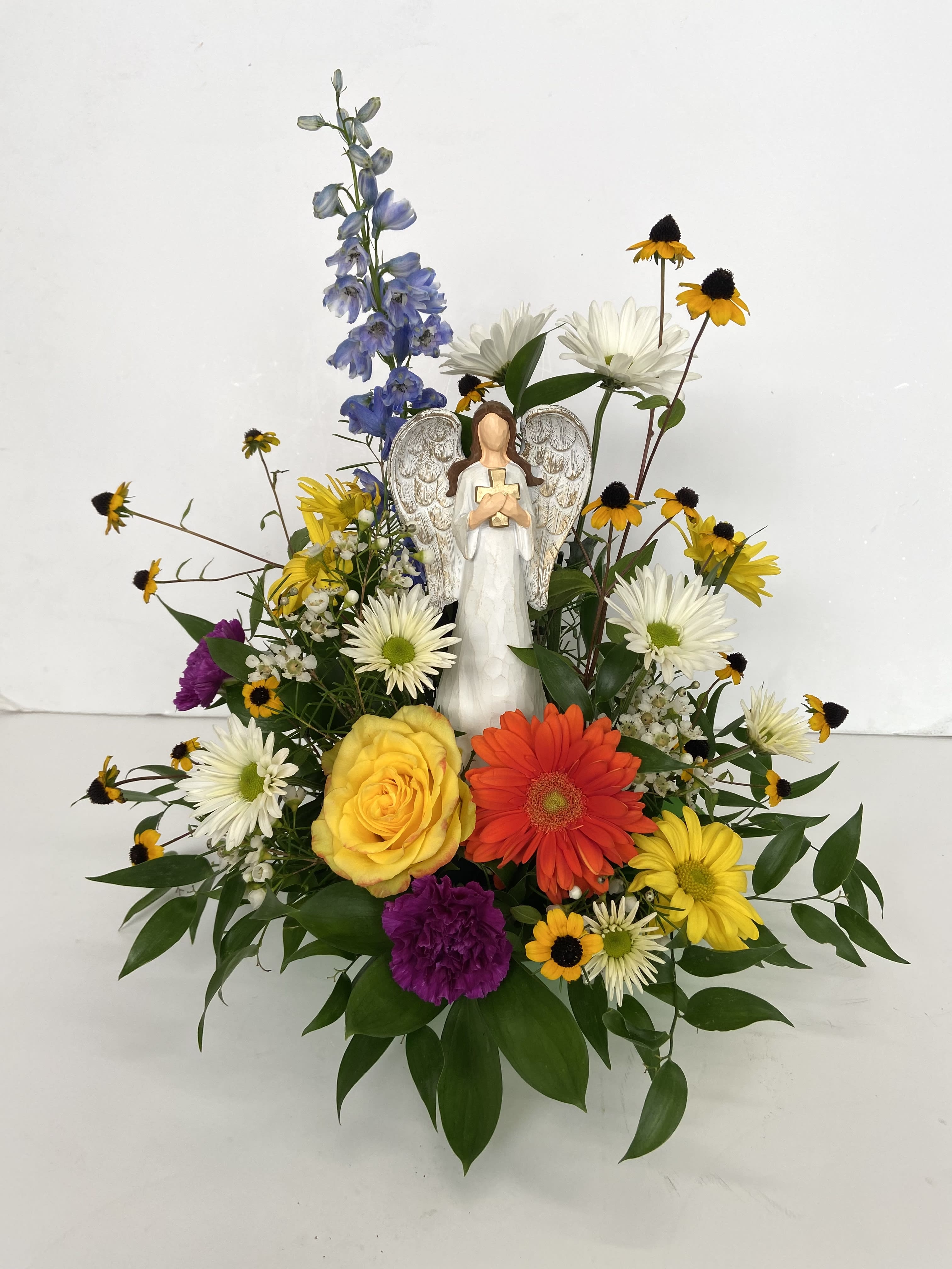 Mixed flower arrangement with an angel figurine in the center