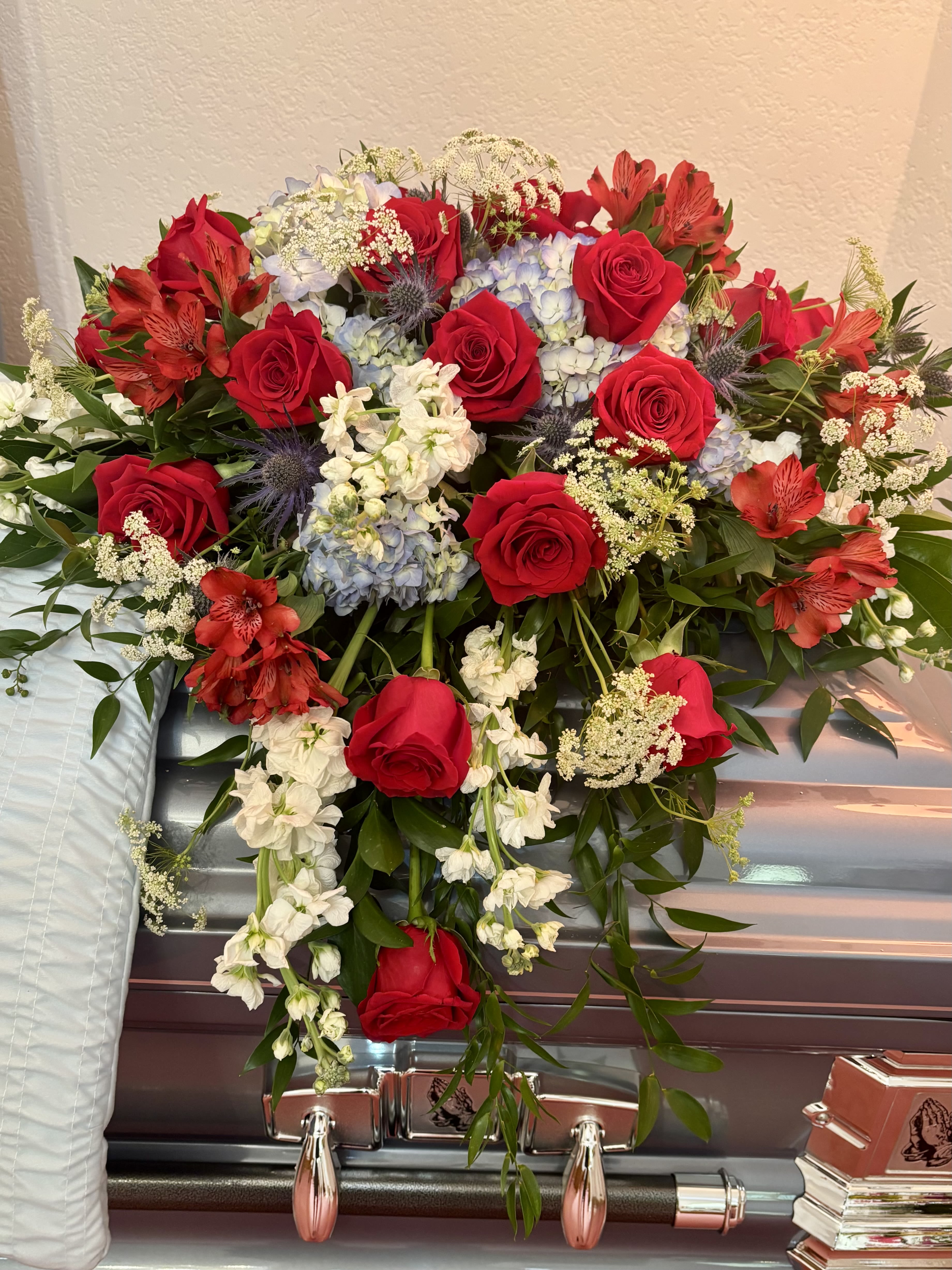 Red roses and red alstroemeria arranged on a silver casket