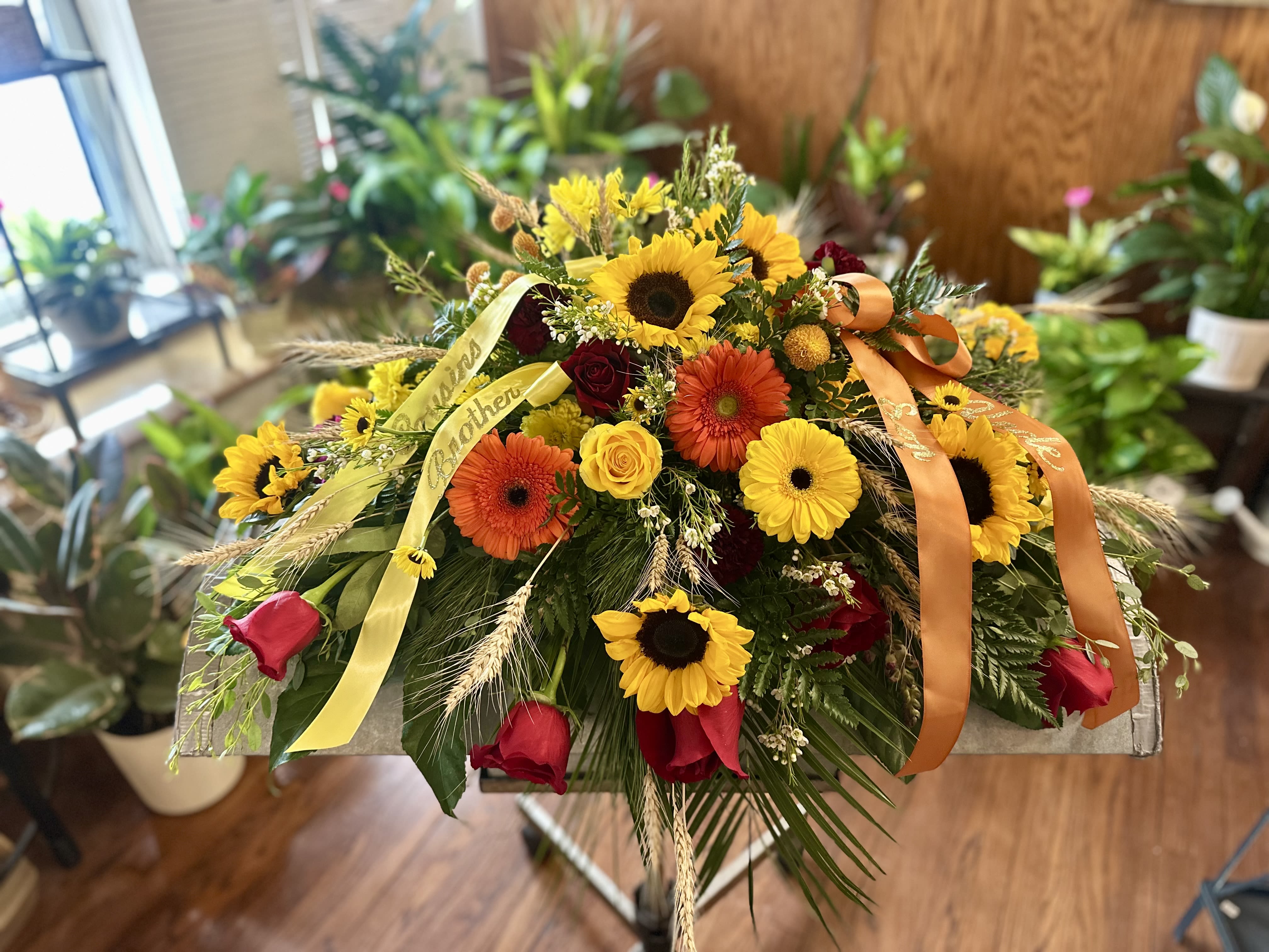 Mixed bouquet with sunflowers, gerbera daisies, and roses on a stand