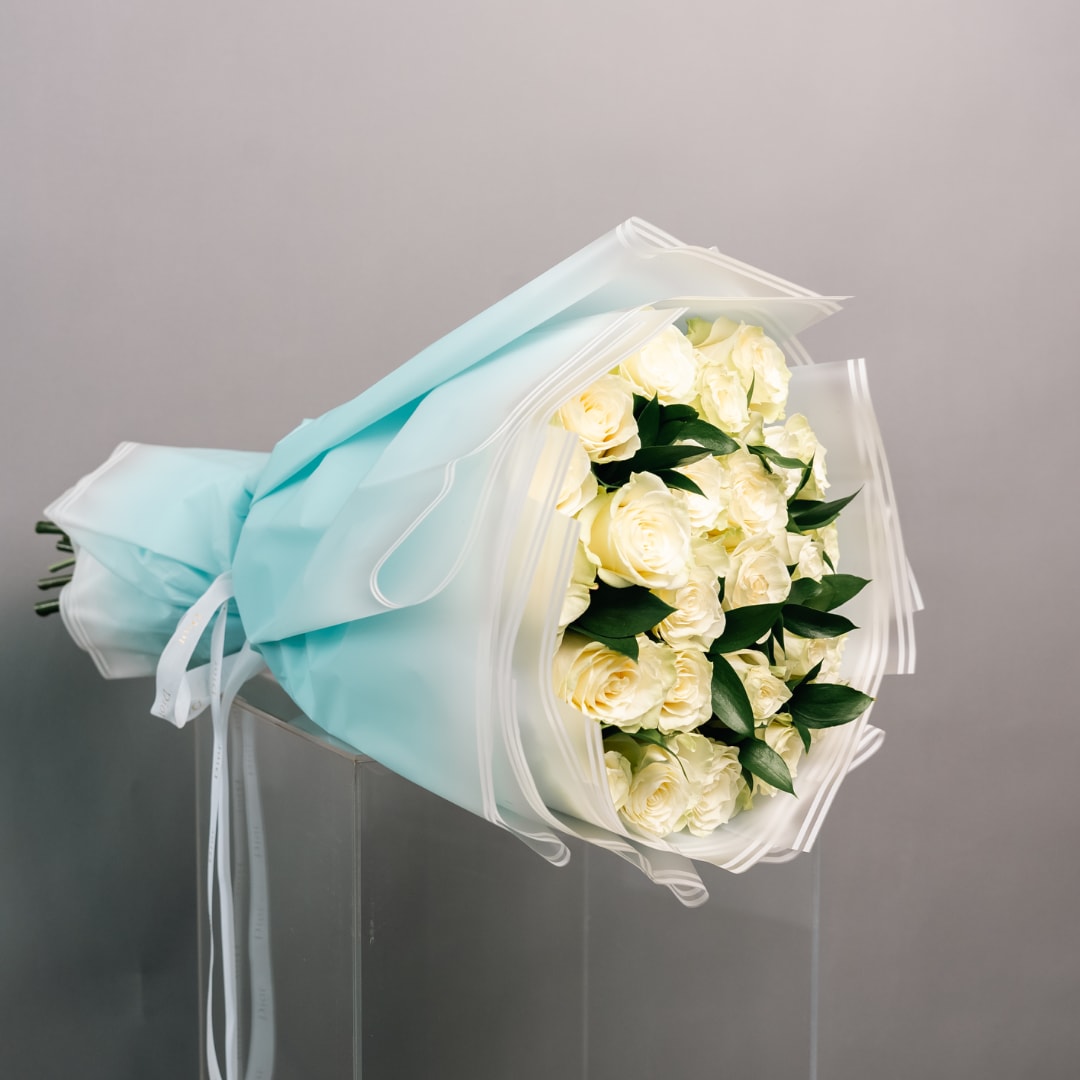 Bouquet of cream roses wrapped in pale blue paper