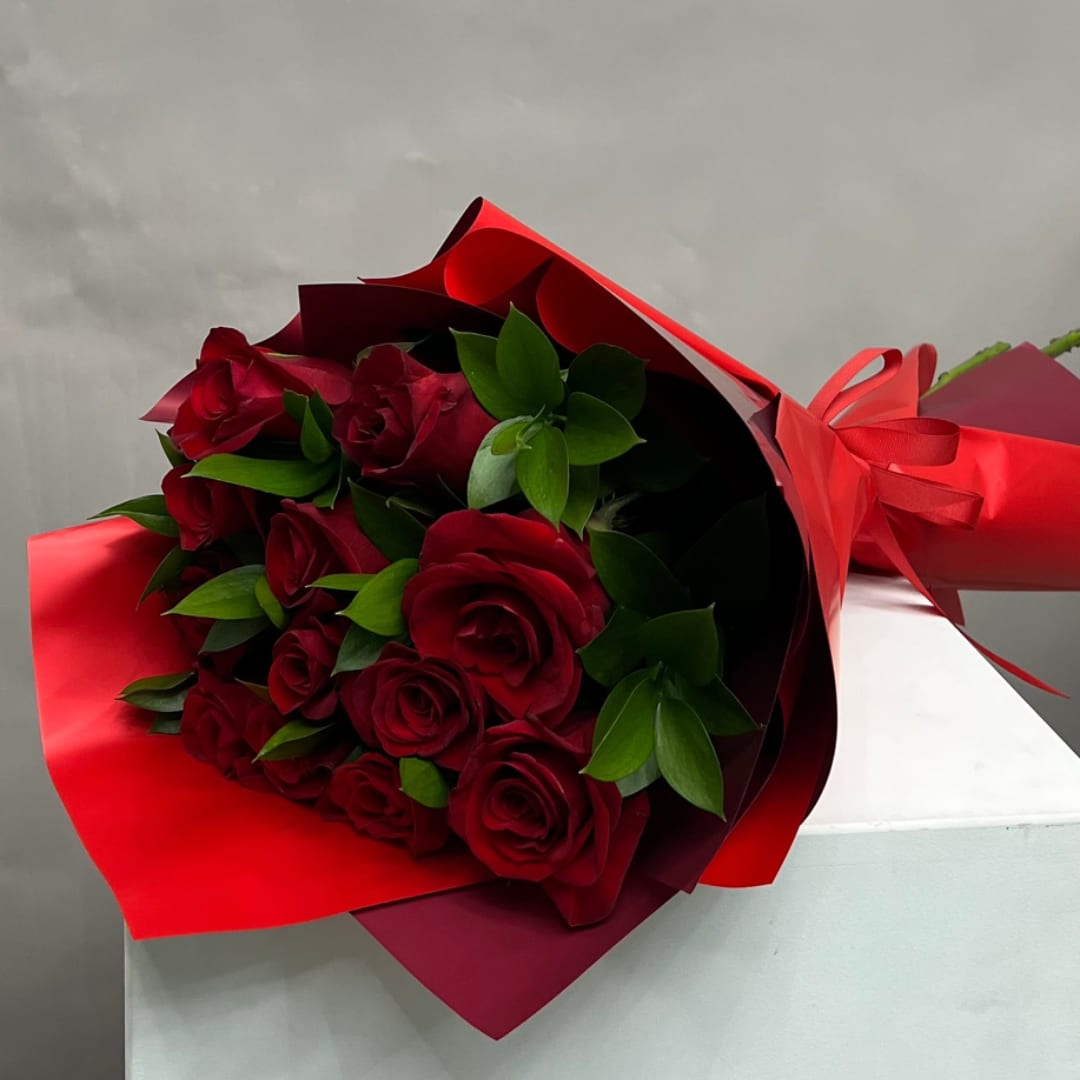 Bouquet of red roses wrapped in red paper with a ribbon