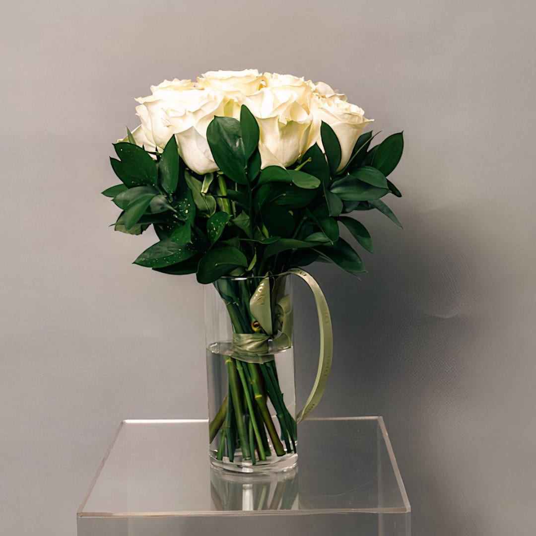 White rose bouquet in a clear glass vase with a ribbon