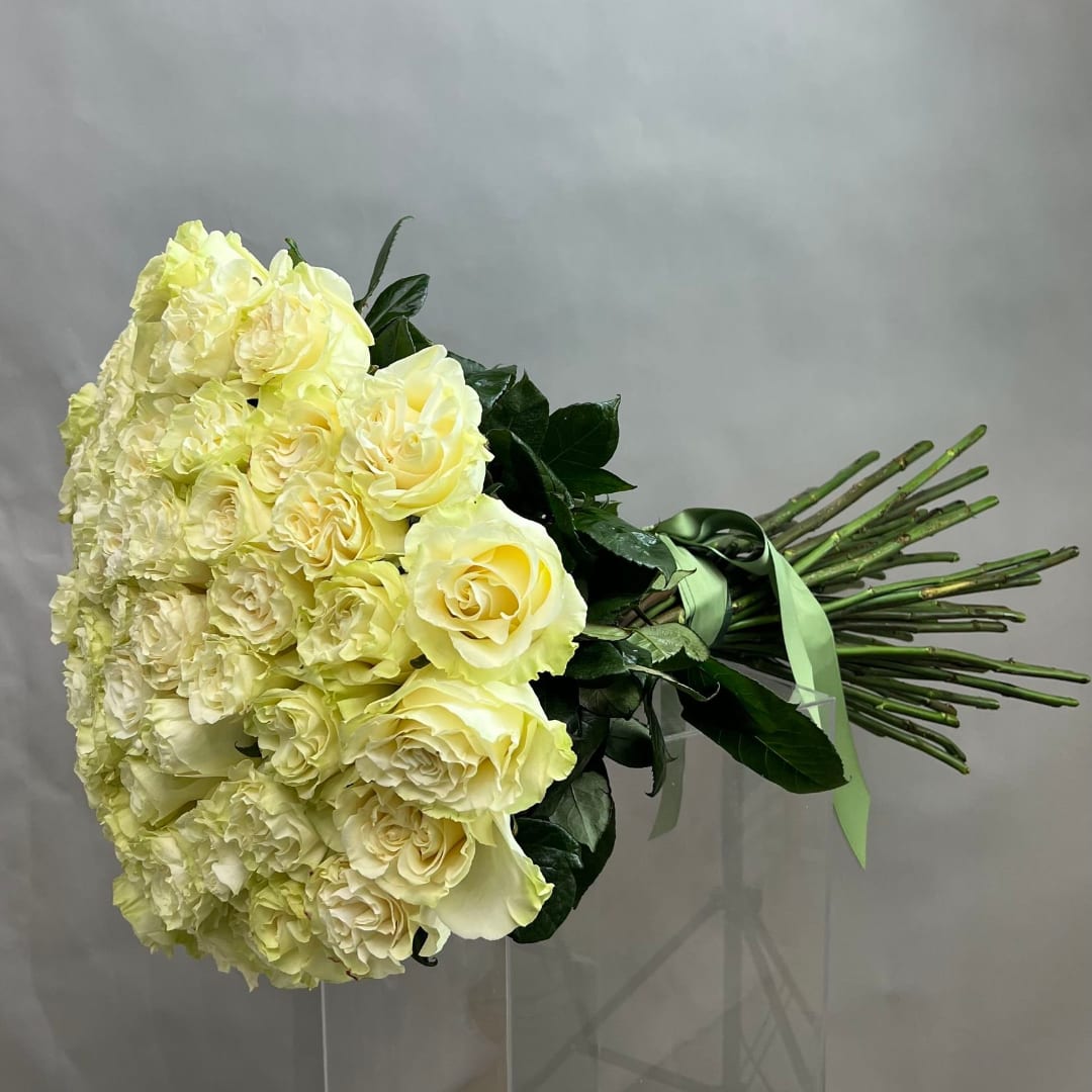 Large bouquet of pale yellow roses and carnations tied with a green ribbon