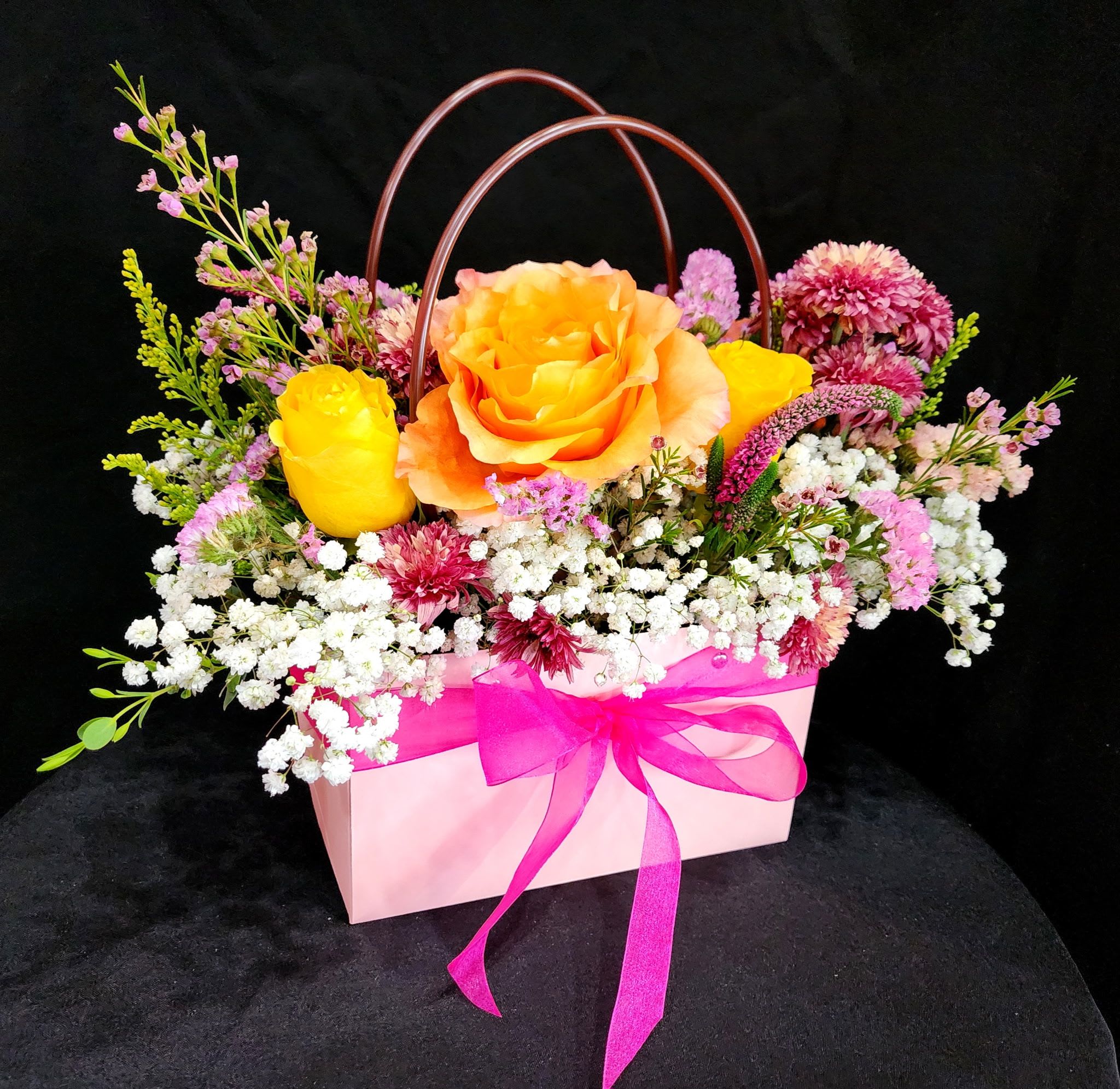 Flower Garden Handbag - Surprise your loved one with this beautiful tote inspired arrangement with gorgeous flowers to make them feel special. This arrangement includes roses, chrysanthemums, wax flowers, veronicas, solidago, babies breath and eucalyptus.  You may also request different colors of roses and choose between 3 colors, pink (9 in stock), black (8 in stock), or white (8 in stock), just be sure to mention which color in special instructions.   Dimensions are approximately: Tote is 13" Height x 8" Length x 4 1/2" Depth. Size with flowers: 11" Height x 10" Length. 